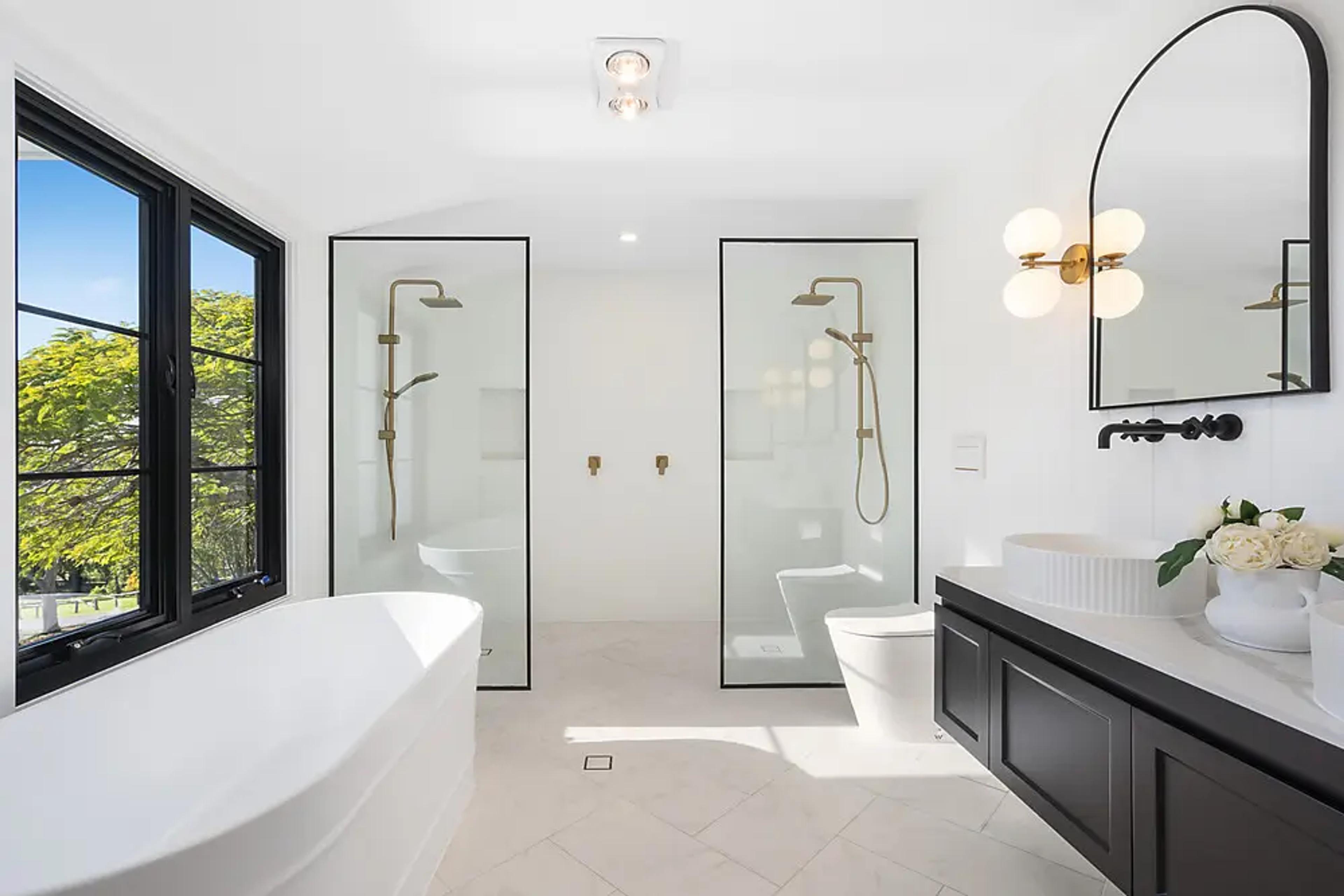 Ensuite with freestanding bath, twin showers and black vanity.
