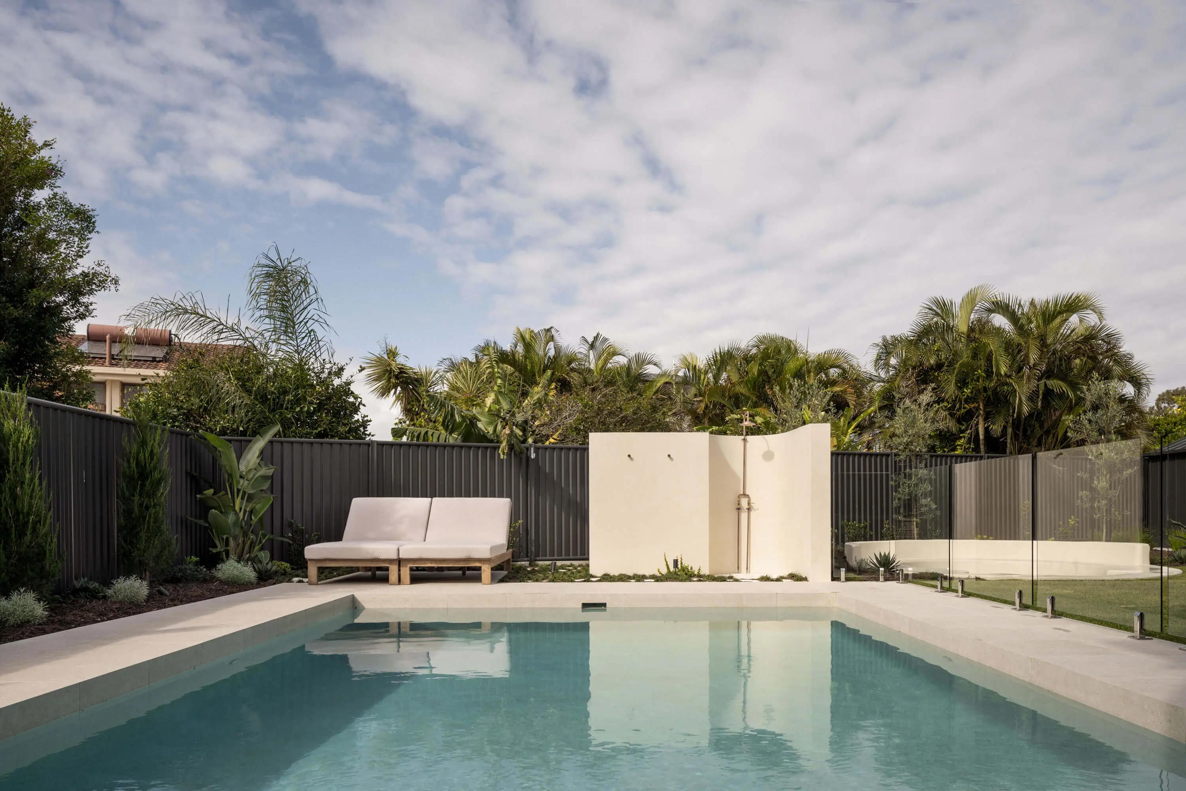 Backyard pool with sun loungers and outdoor shower