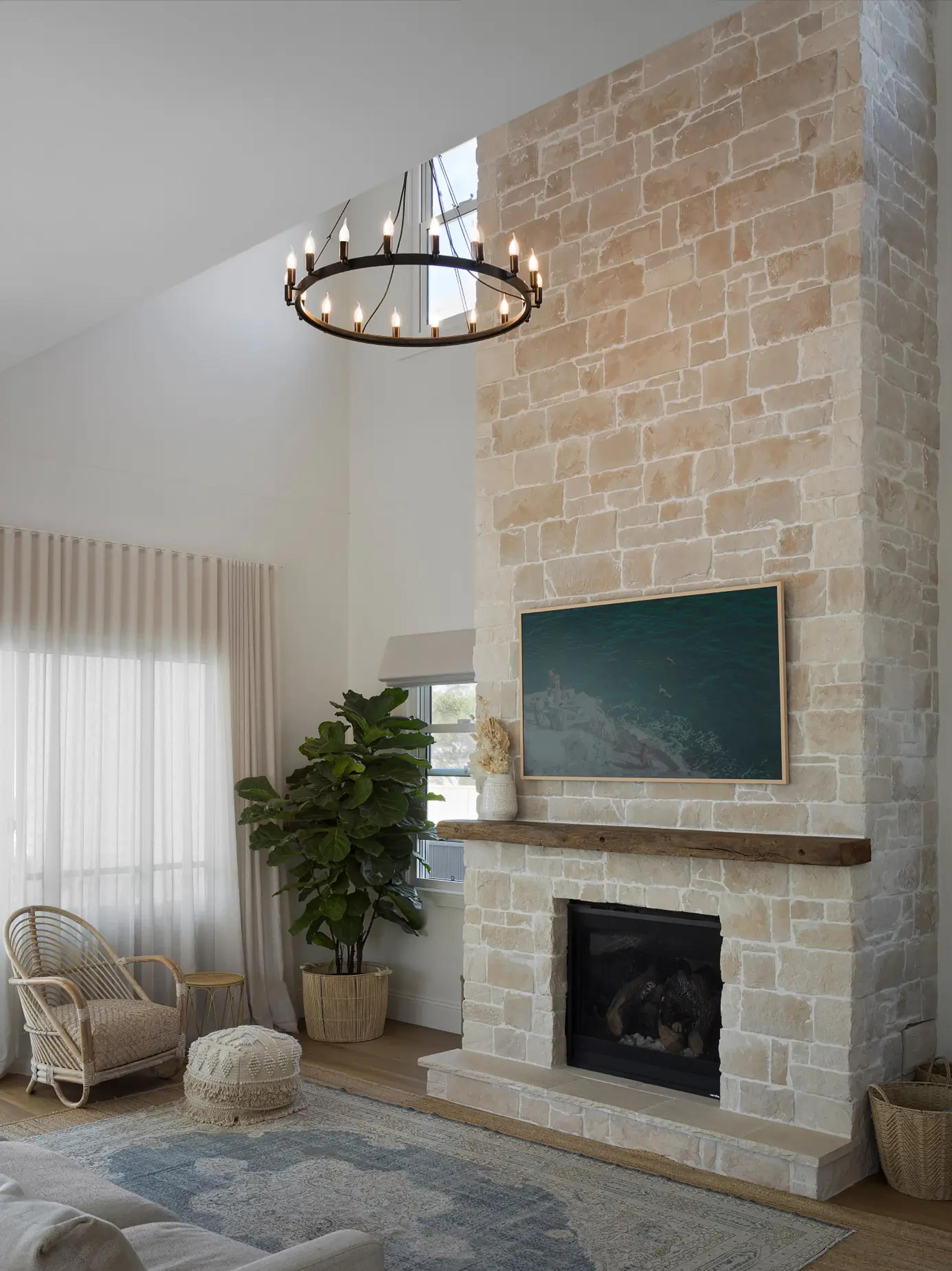 Living room with stone fireplace, chandelier and rattan armchair