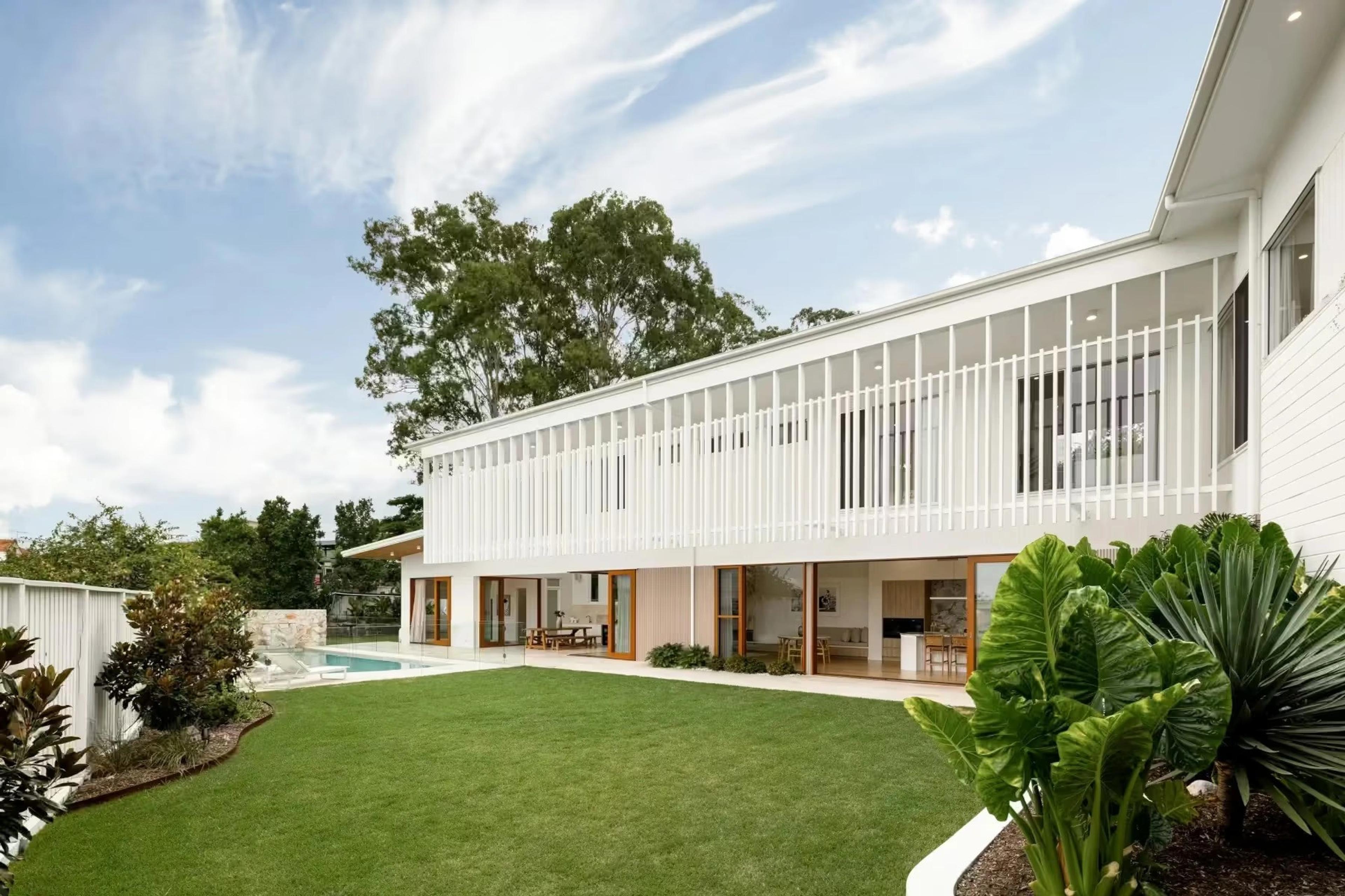 Backyard view of home with battened upper level and green lawn