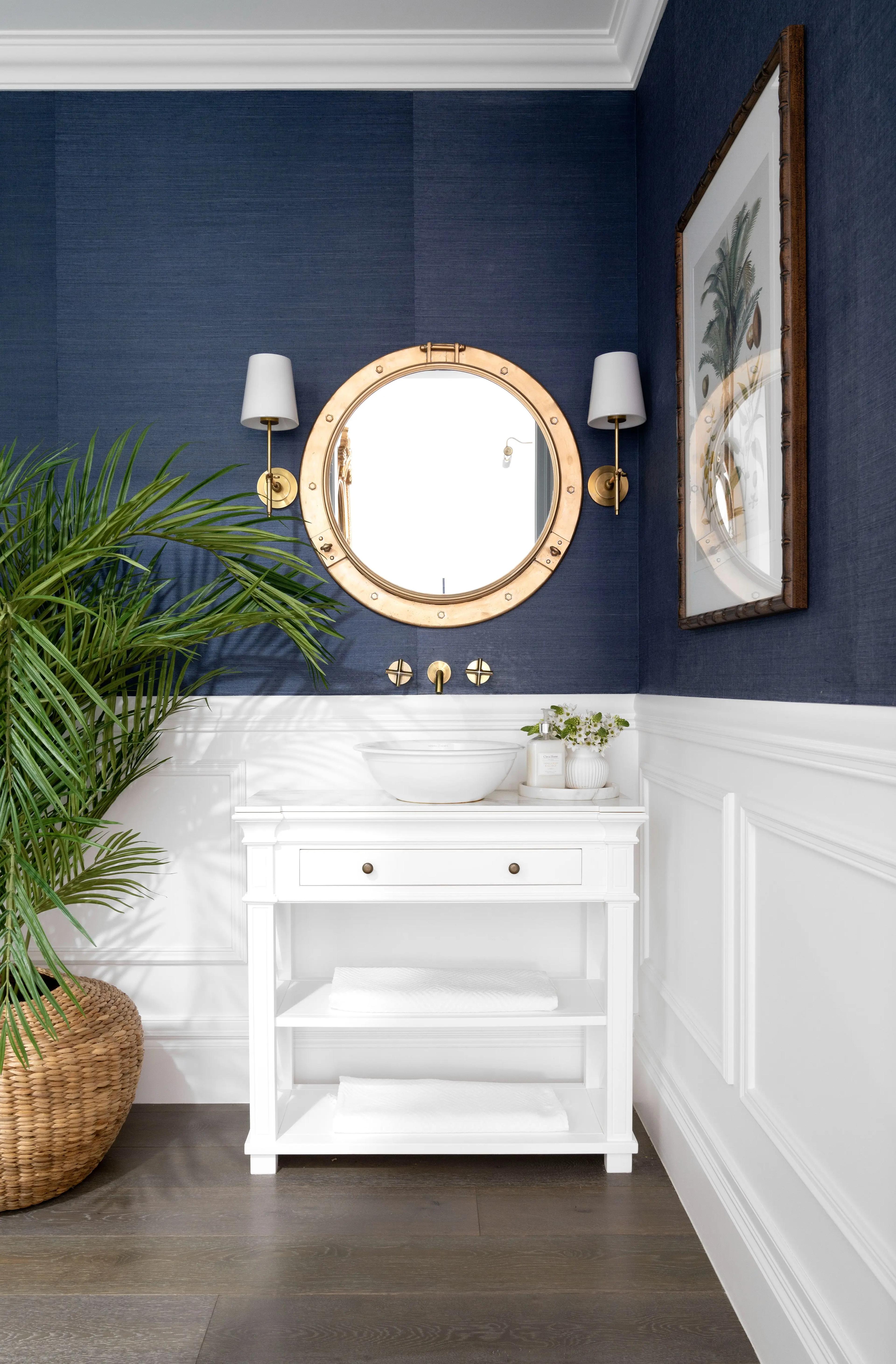 Powder room with navy grasscloth walls and brass porthole mirror