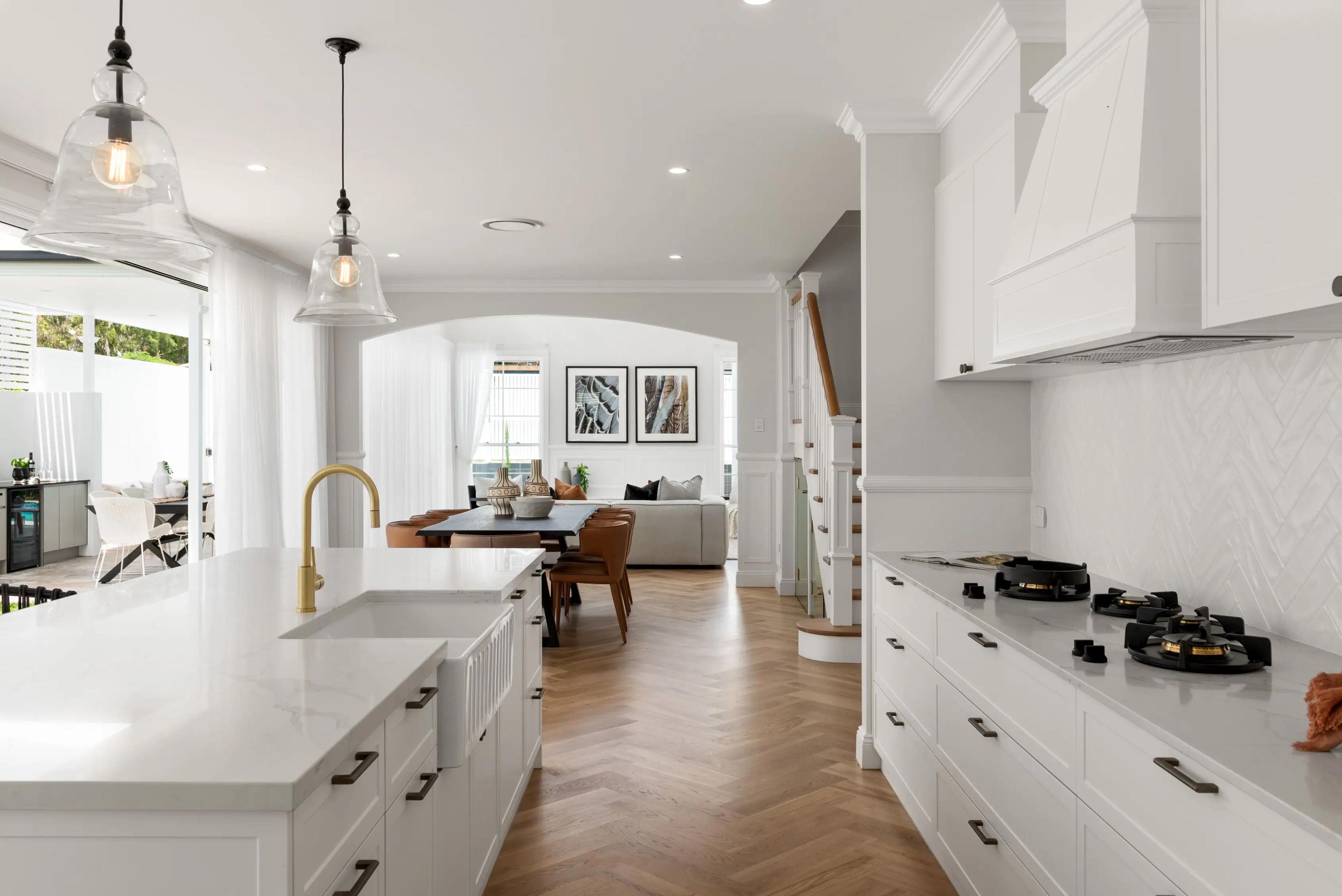 White kitchen with island bench, gas cooktop and pendant lights