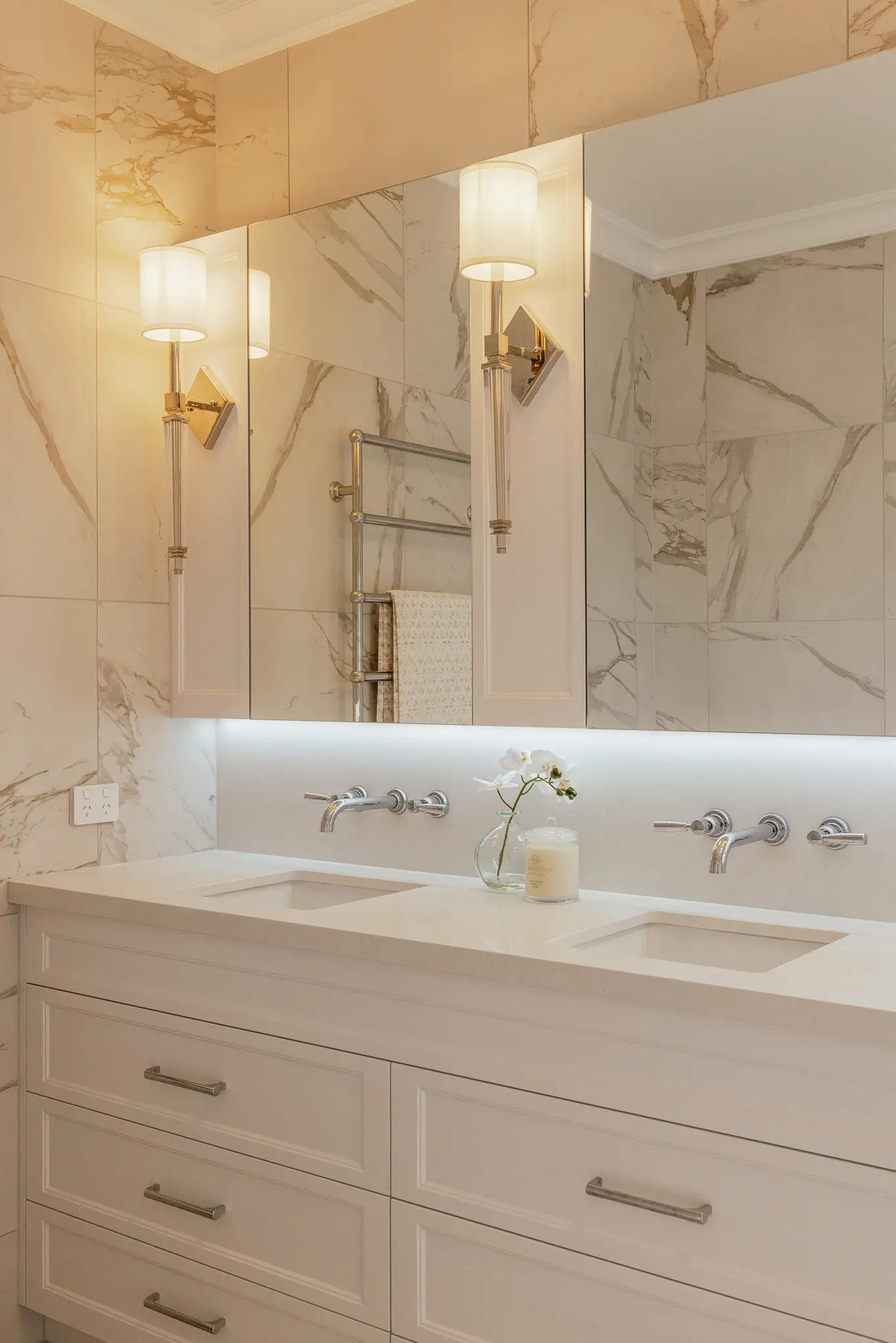 Marble ensuite bathroom with double basins and wall sconces