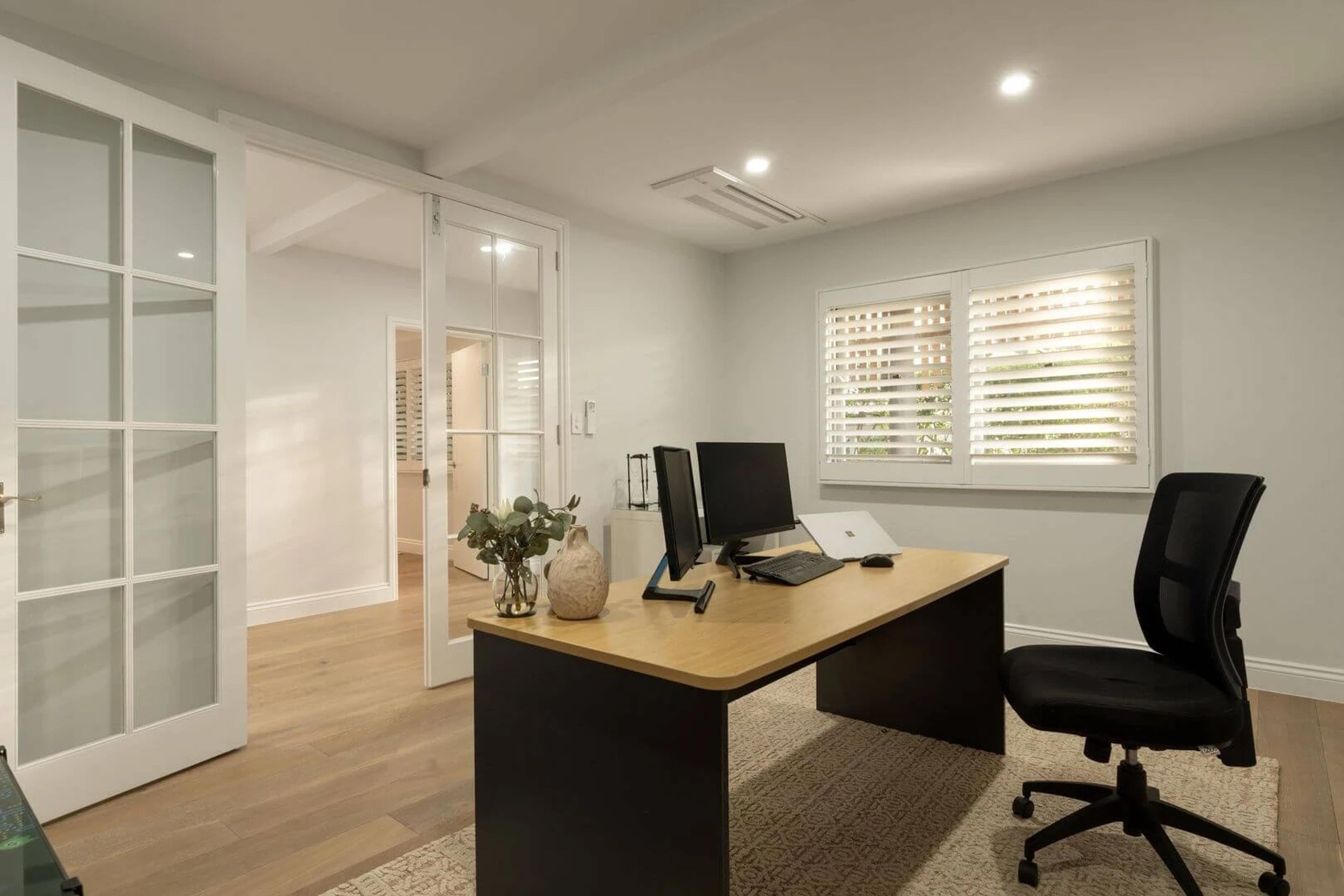 Home office with timber desk, monitors and glass panelled doors