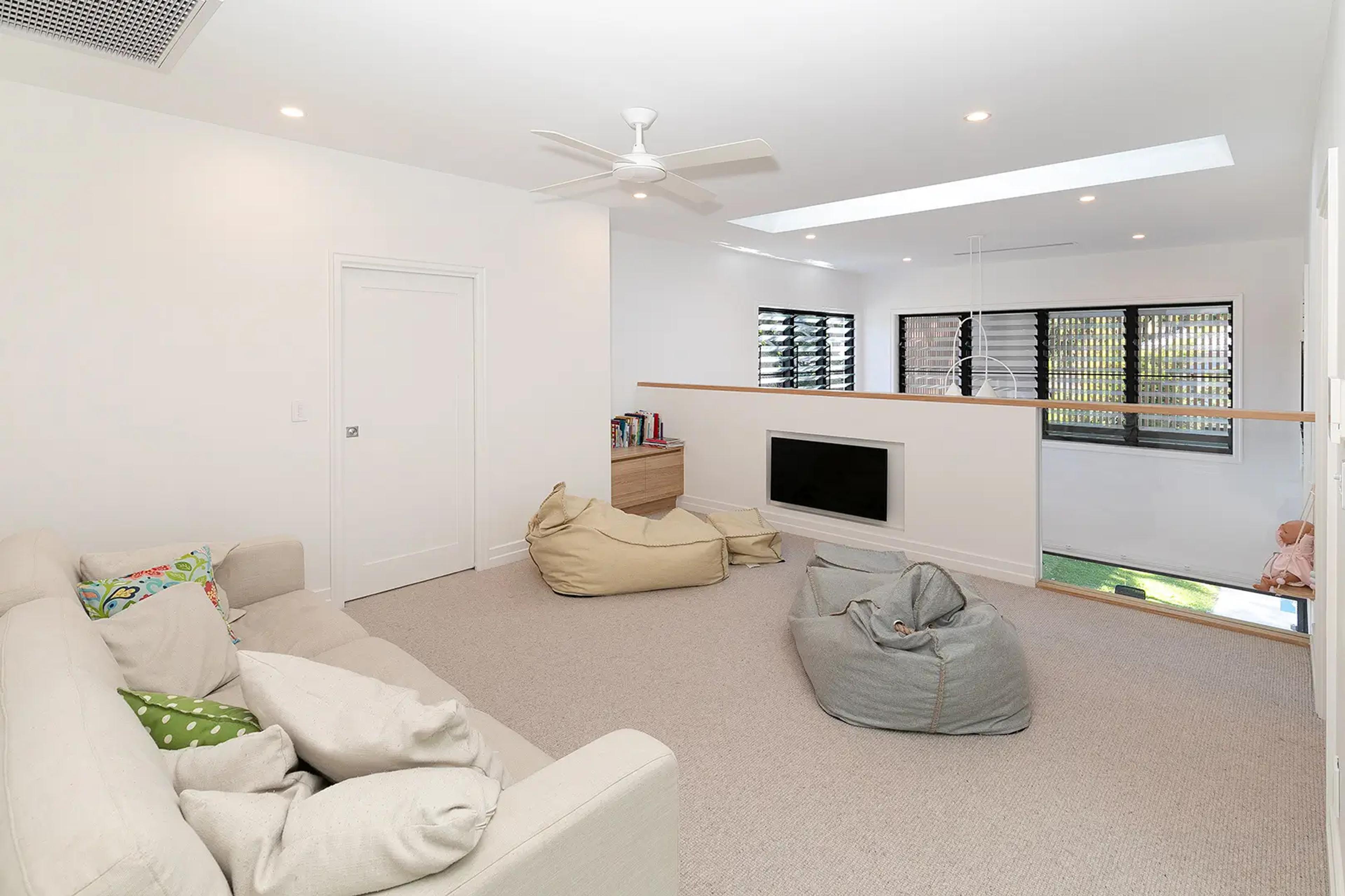 Carpeted upstairs rumpus room with beanbags and wall mounted television
