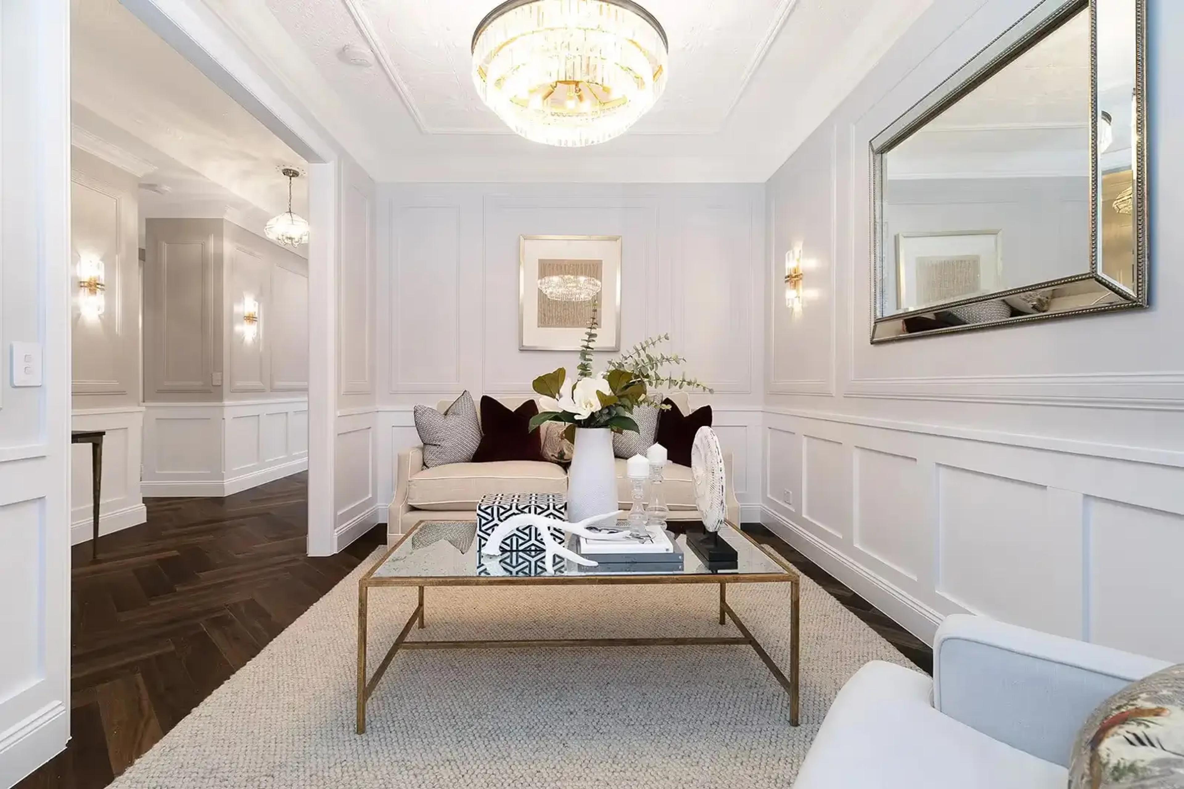 Formal sitting room with panelled walls and gold framed mirror