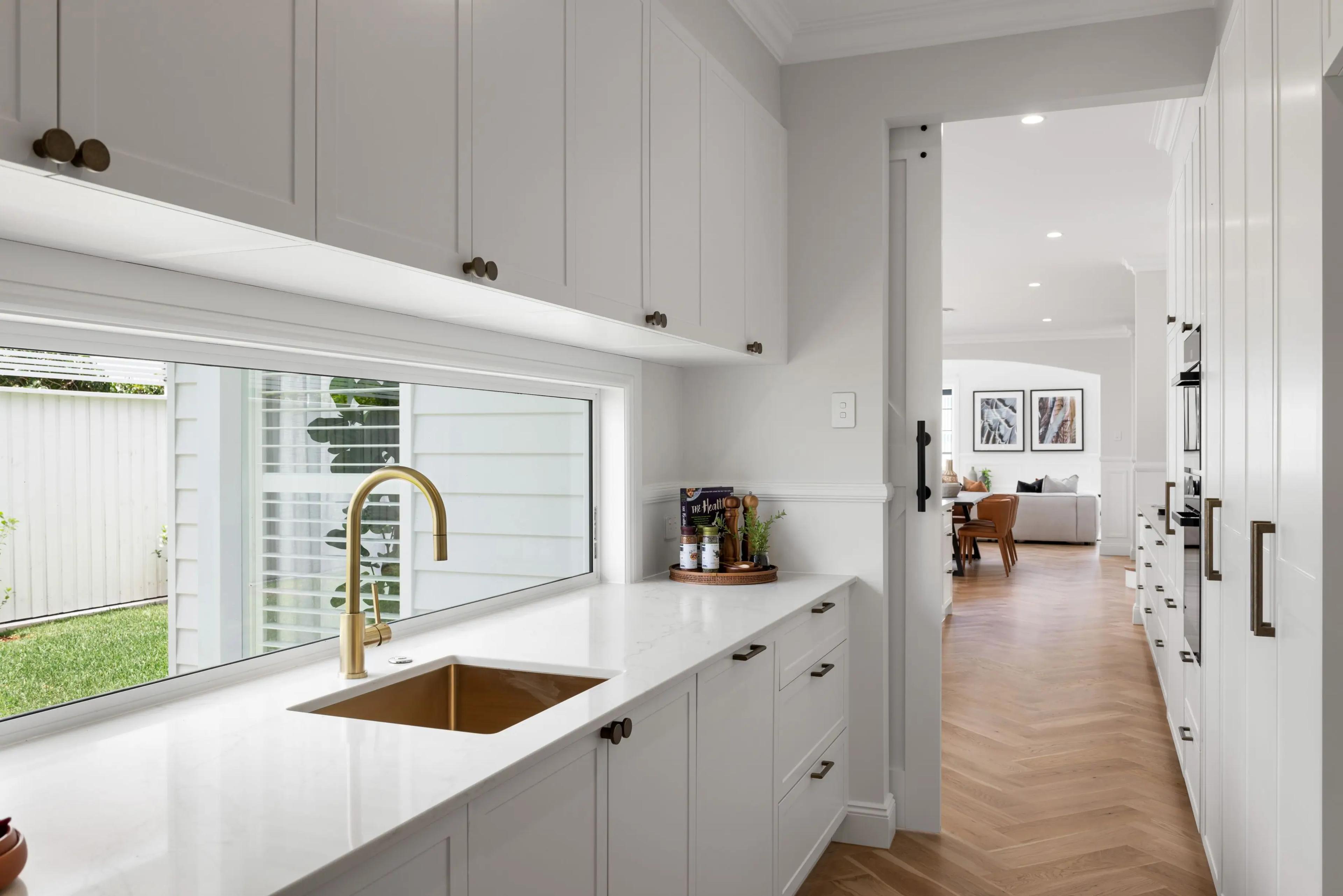 Butlers pantry with white cabinetry and brass tapware over sink