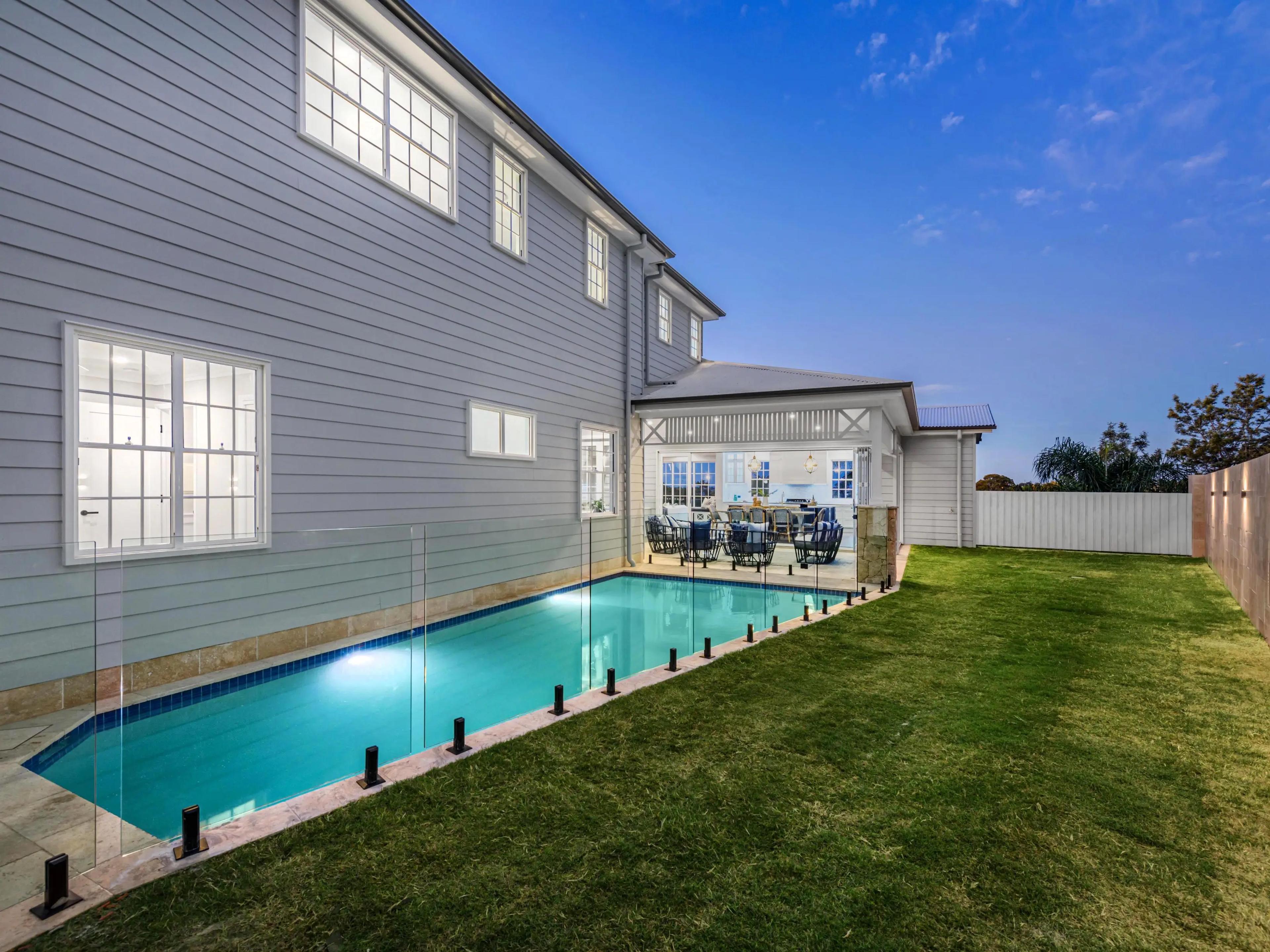 Rear of home with fenced swimming pool and lawn