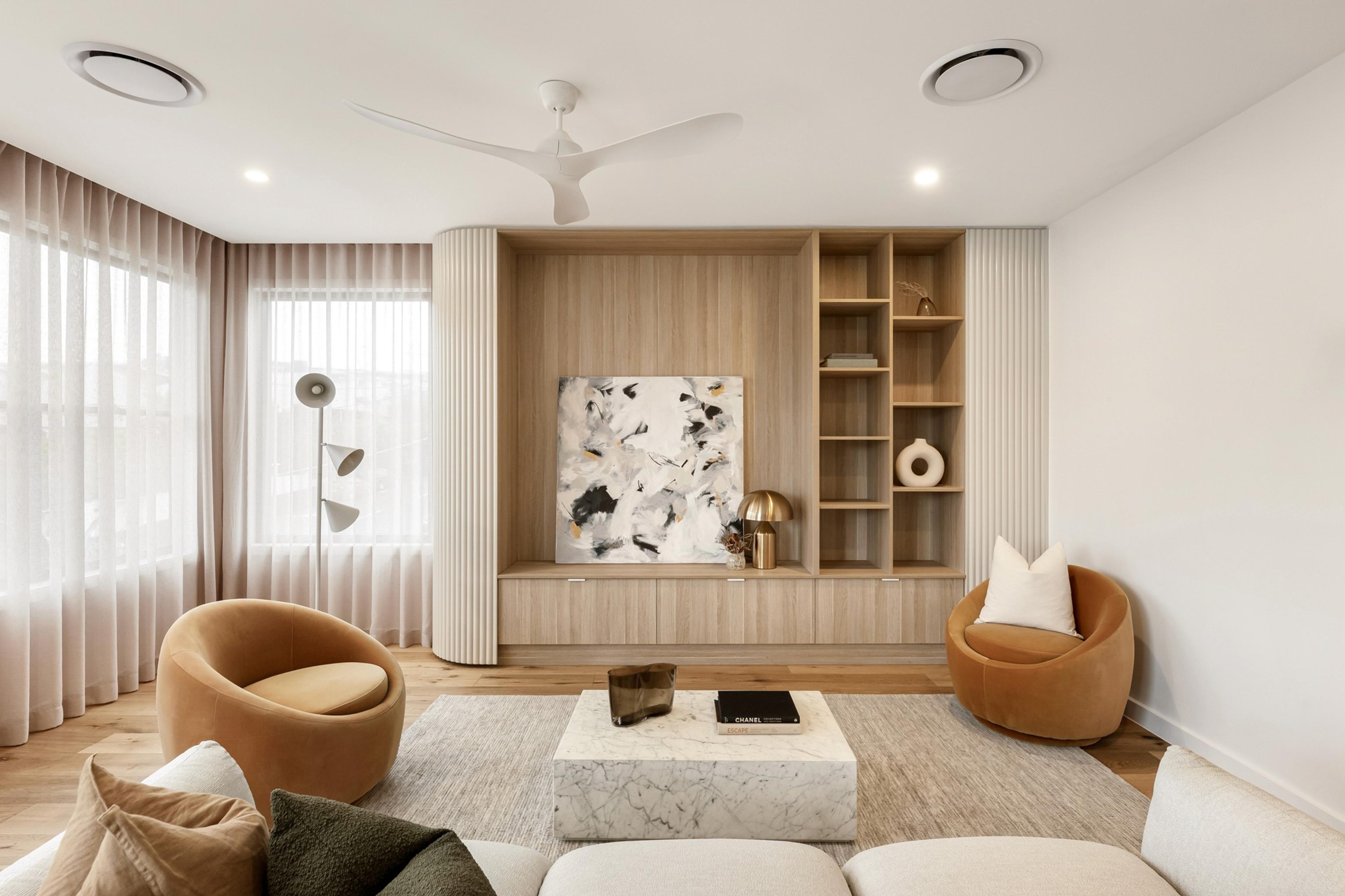 Living room with tan armchairs, marble coffee table and built in shelving