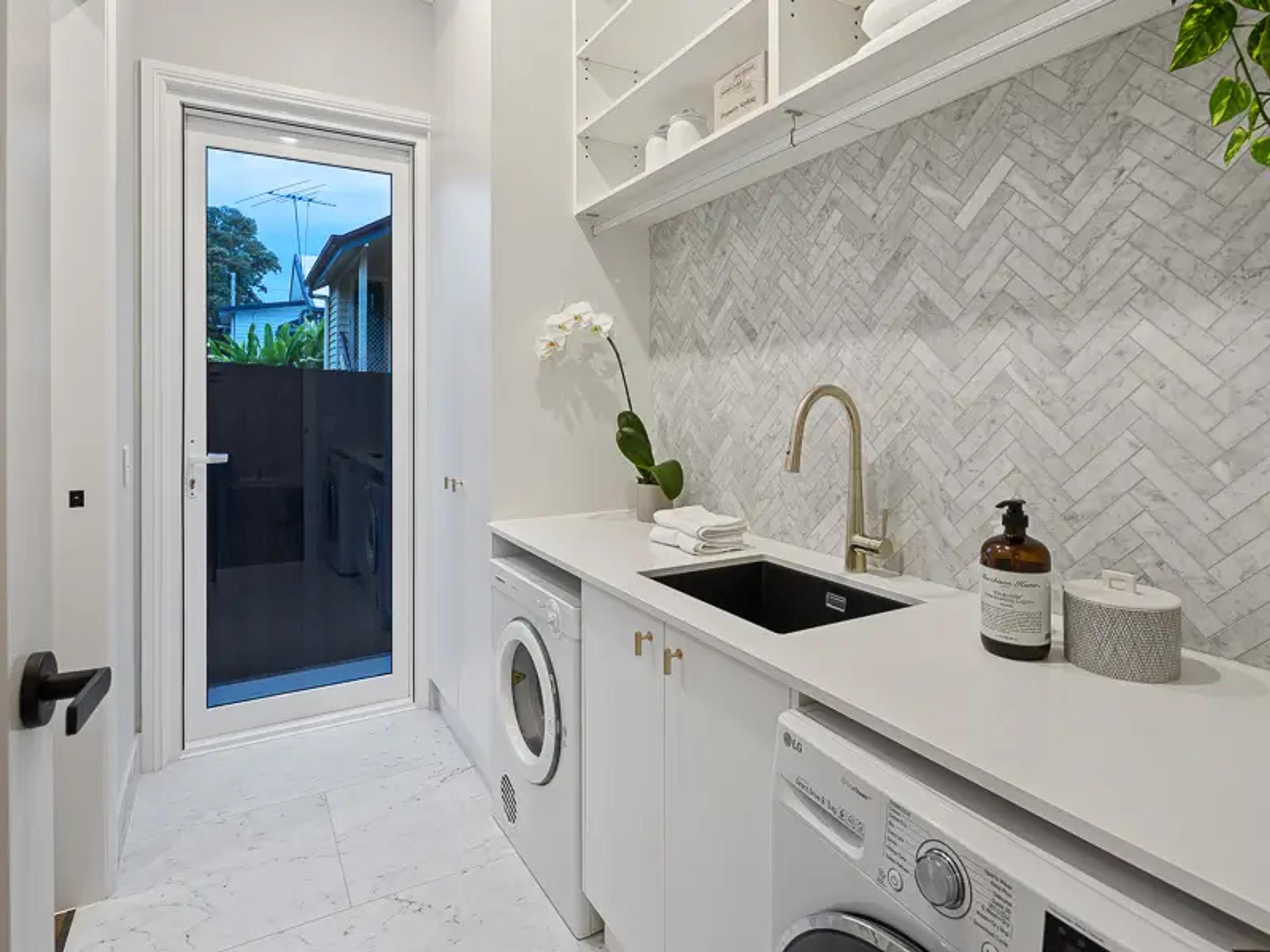 Laundry with marble splashback, sink and external glass door