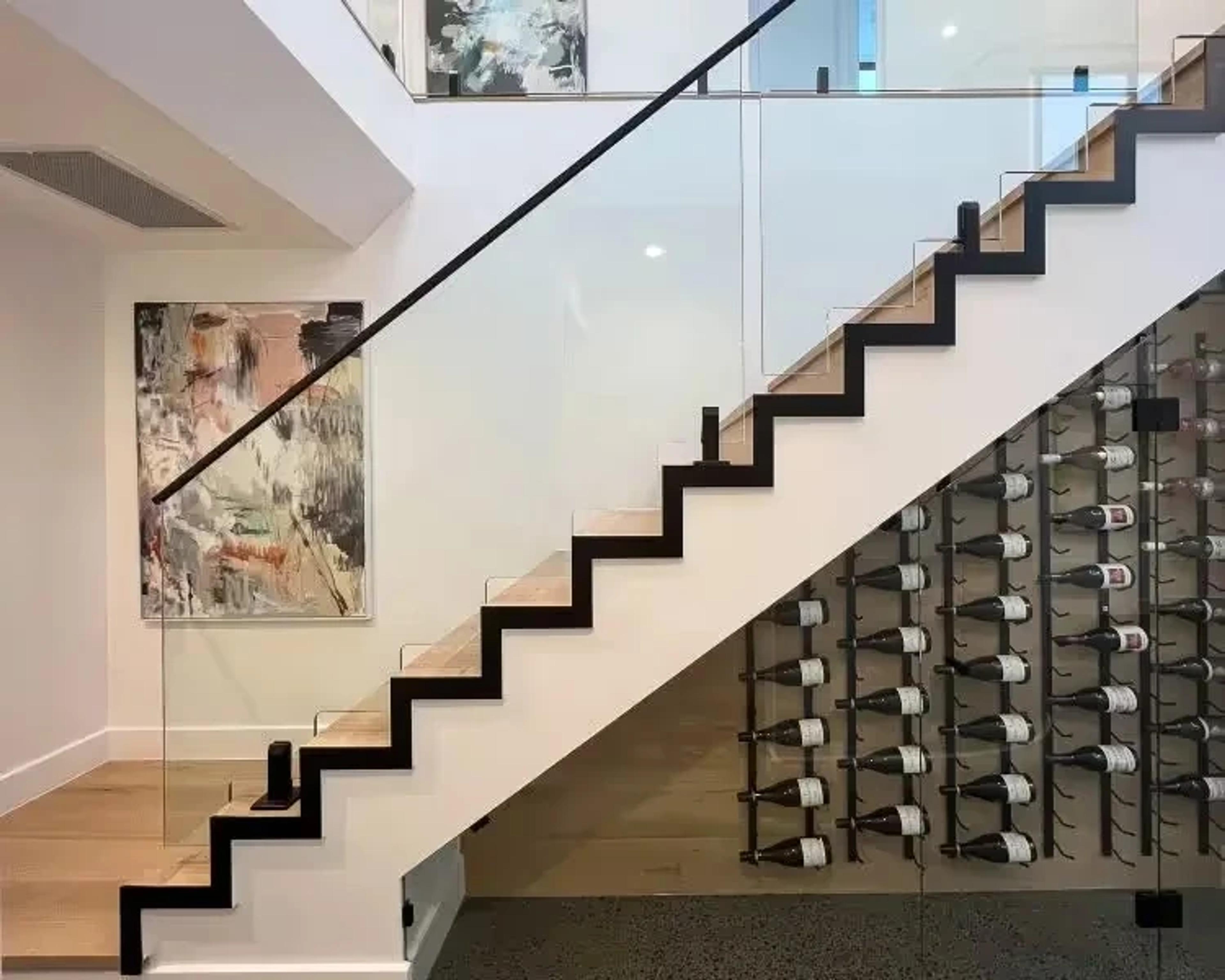 Floating staircase beside glass fronted wine storage wall