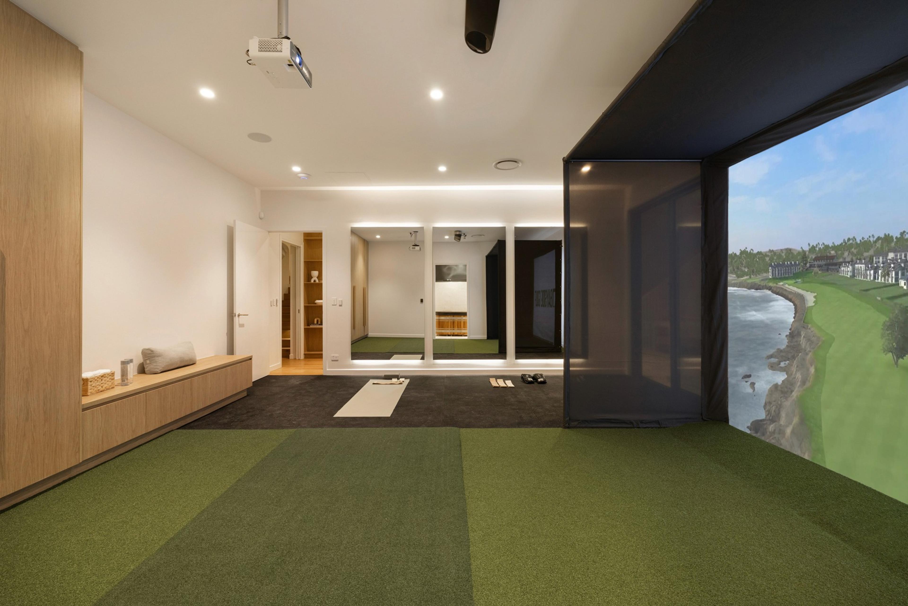 Golf simulator room with green flooring and screen