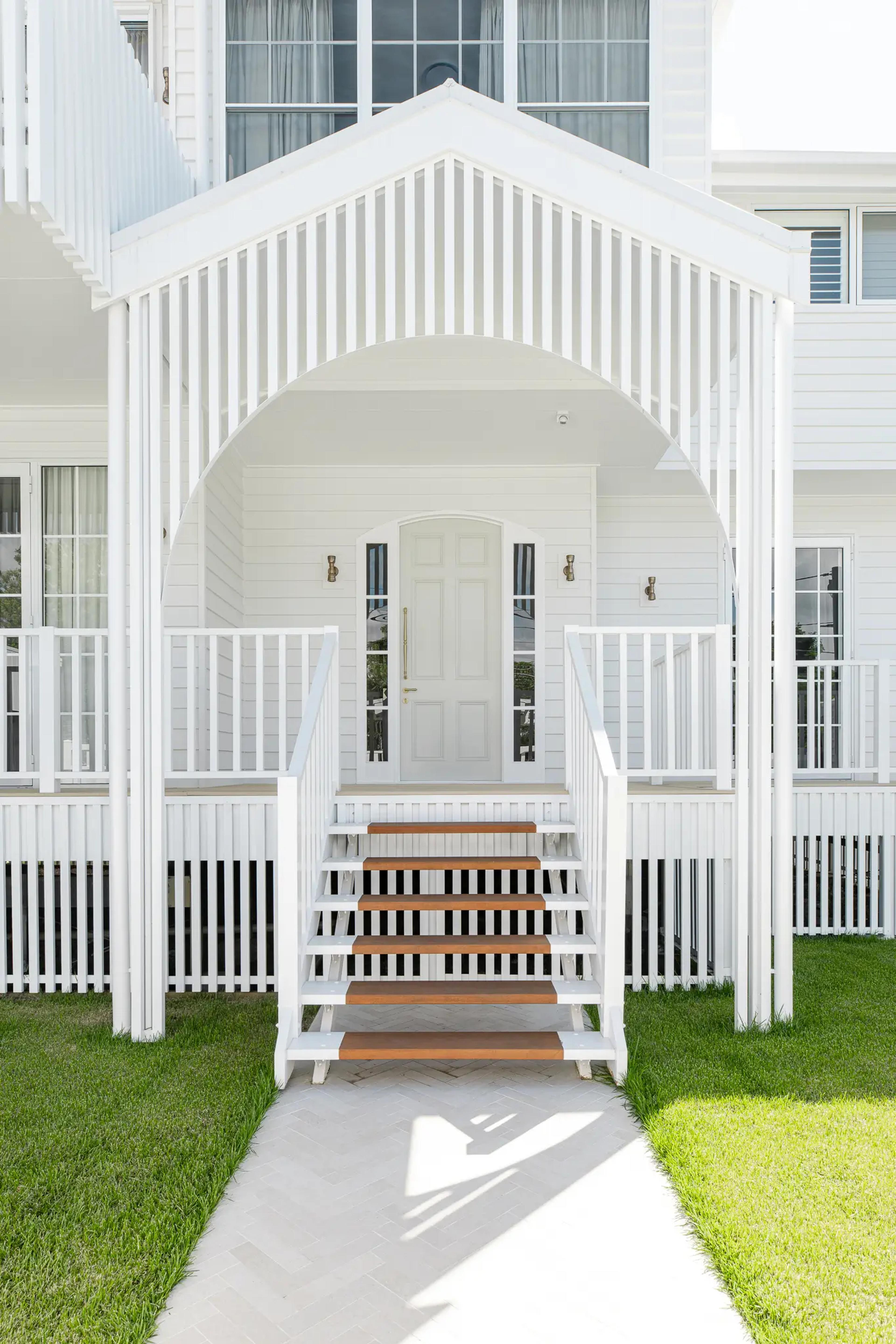 White weatherboard home front entry with gabled porch and timber steps