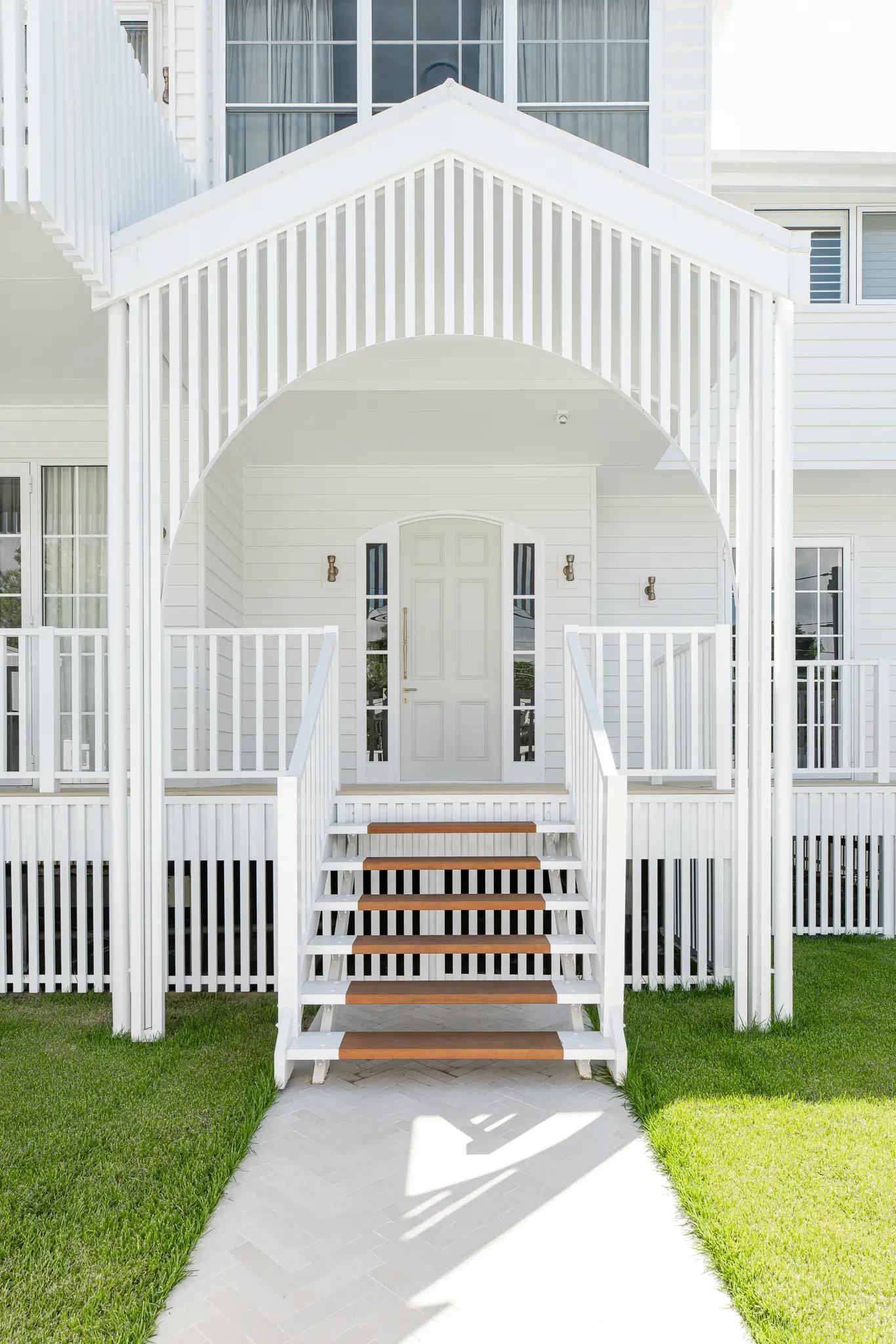 White weatherboard home front entry with gabled porch and timber steps