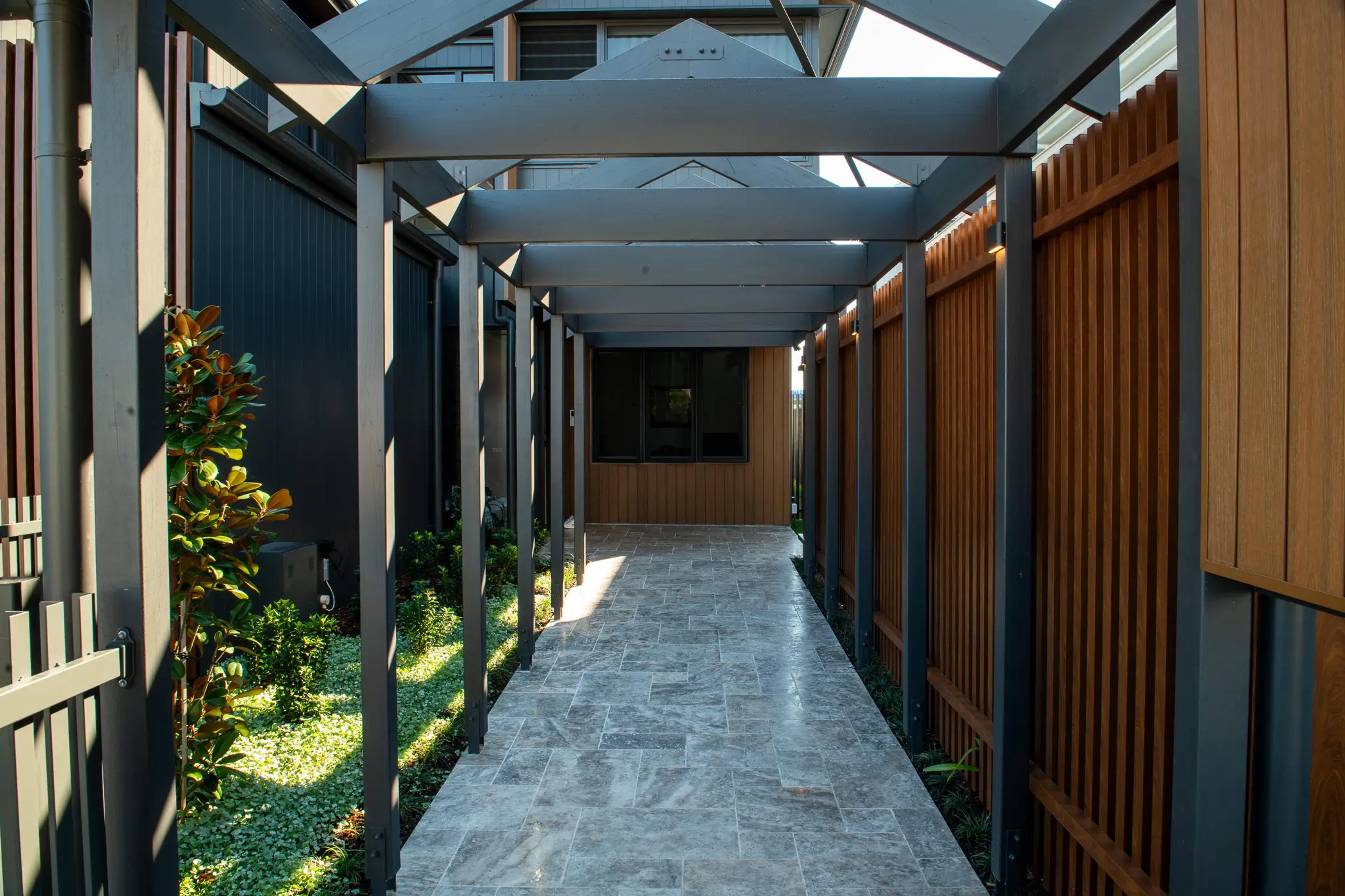 Covered side walkway with pergola and stone paving