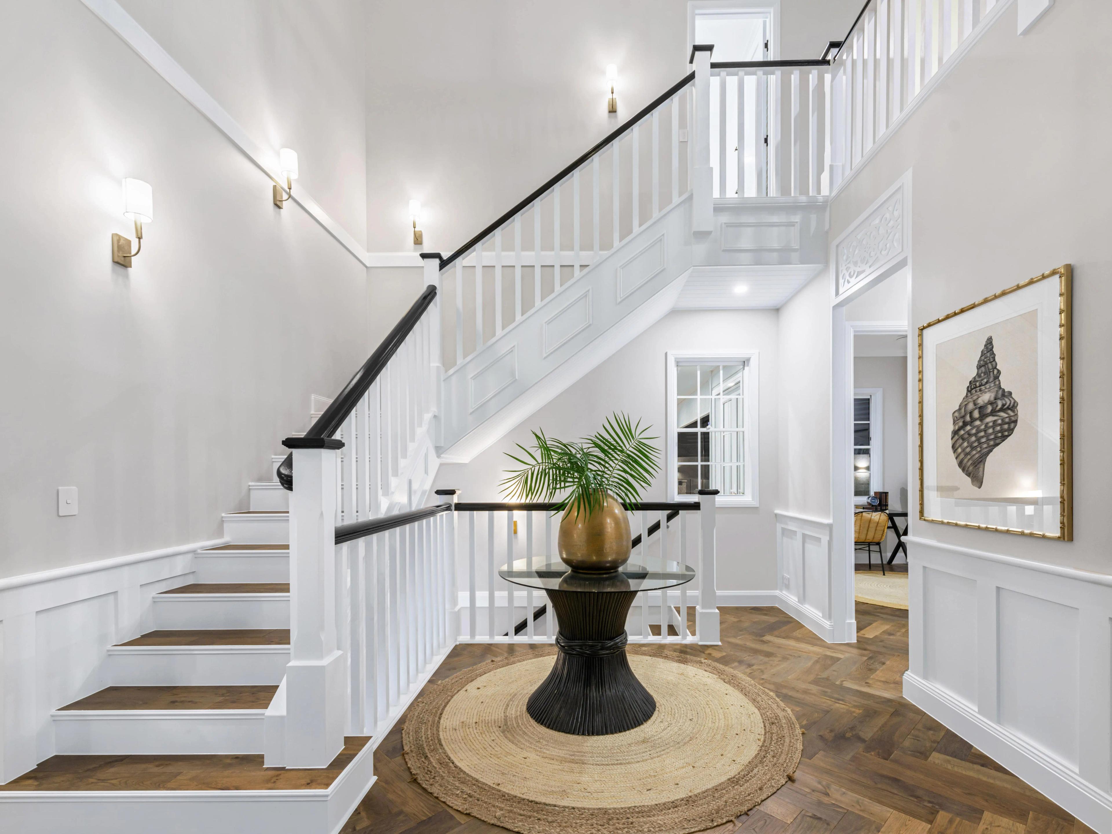 Entry foyer with white timber staircase and round rug