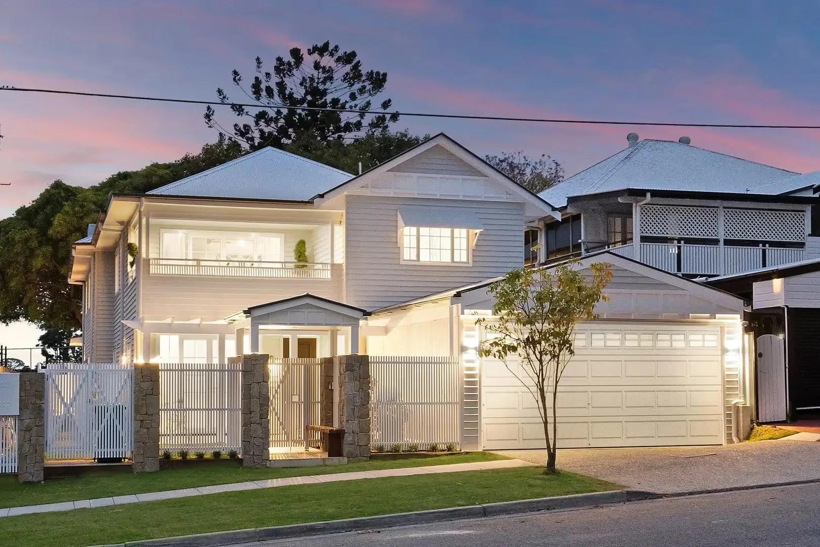 Two storey white weatherboard home facade at dusk with double garage