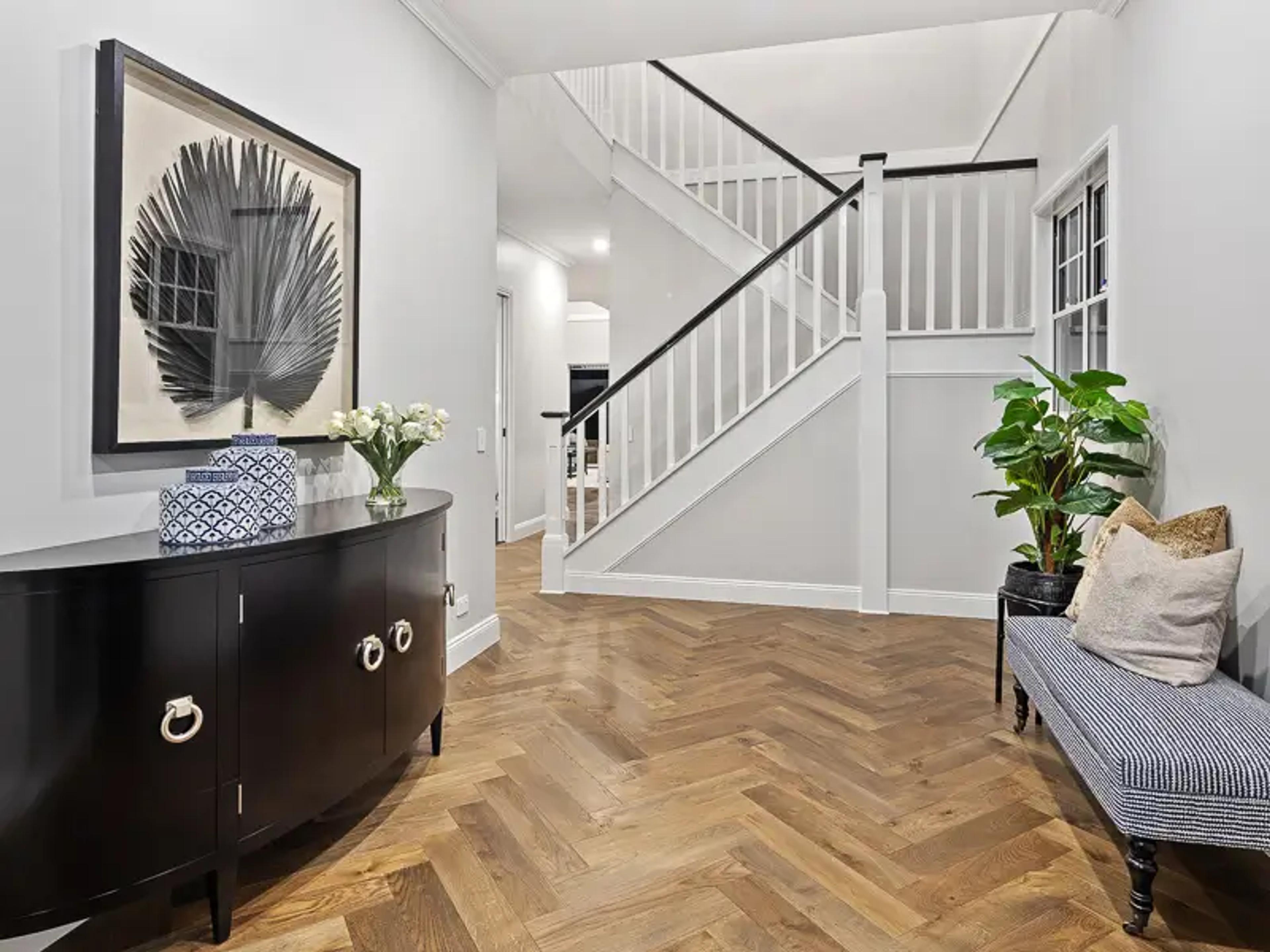 Entry foyer with timber staircase and curved sideboard