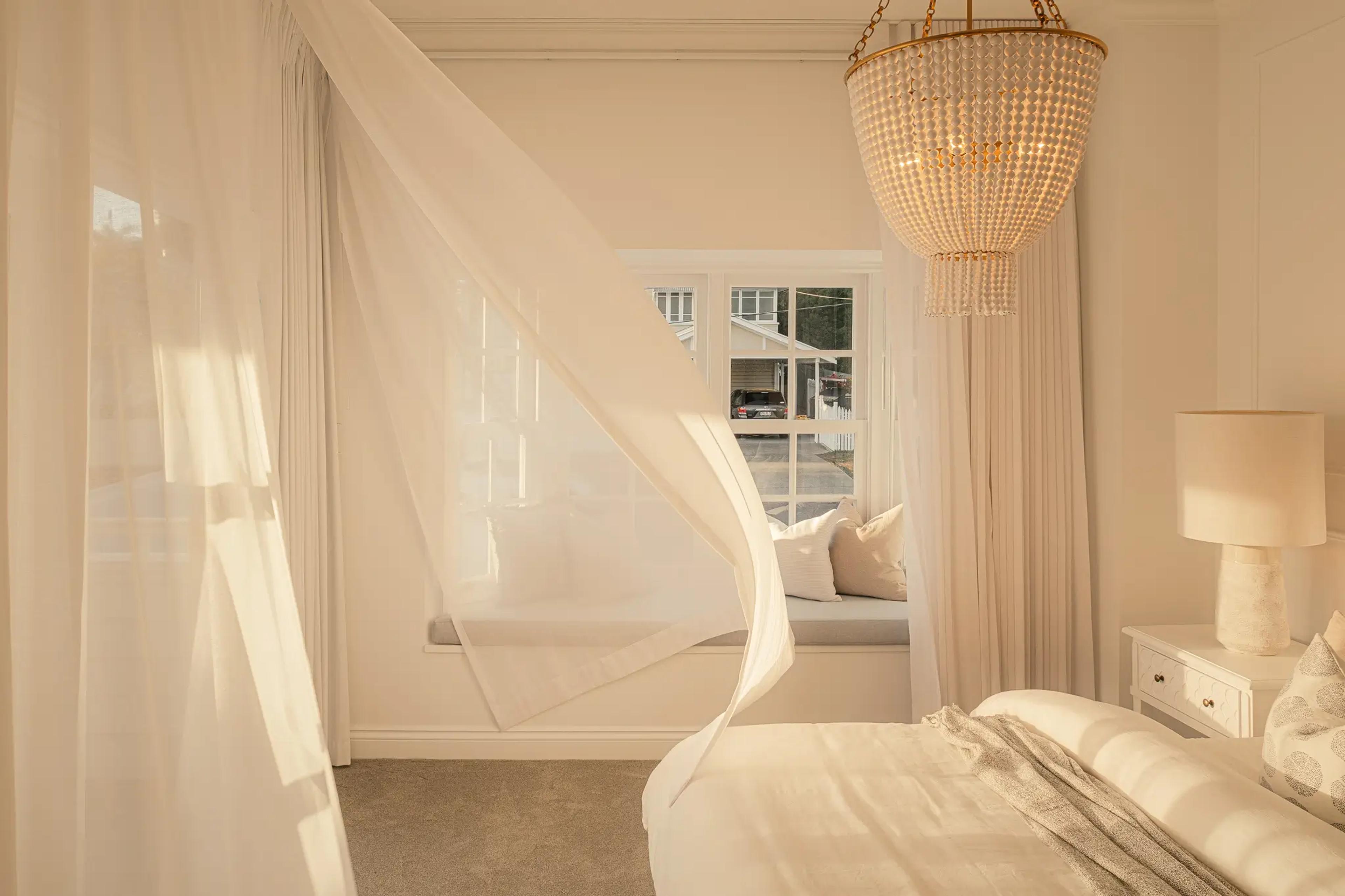 Bedroom with canopy bed, window seat and beaded chandelier