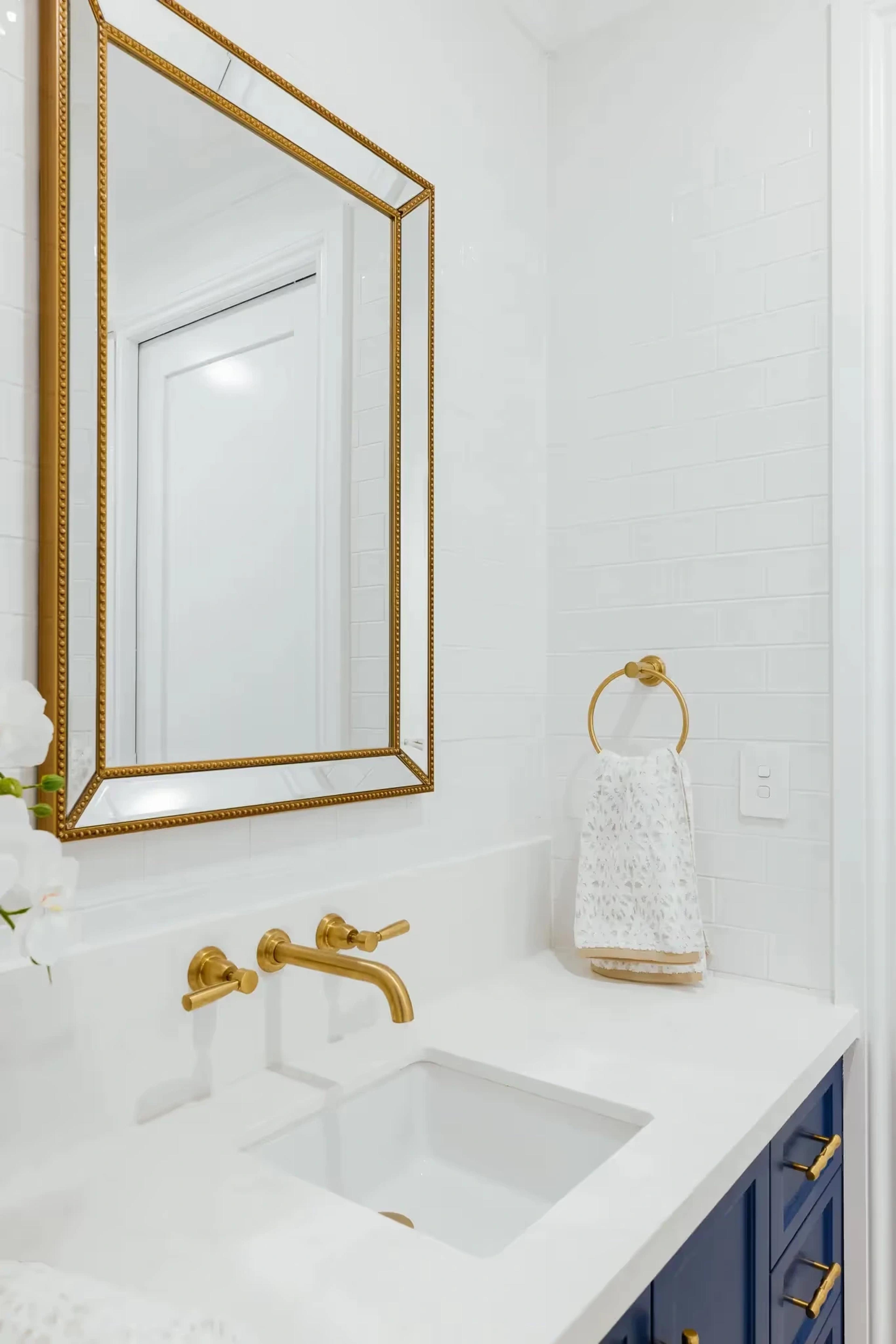 Powder room with gold mirror and navy vanity