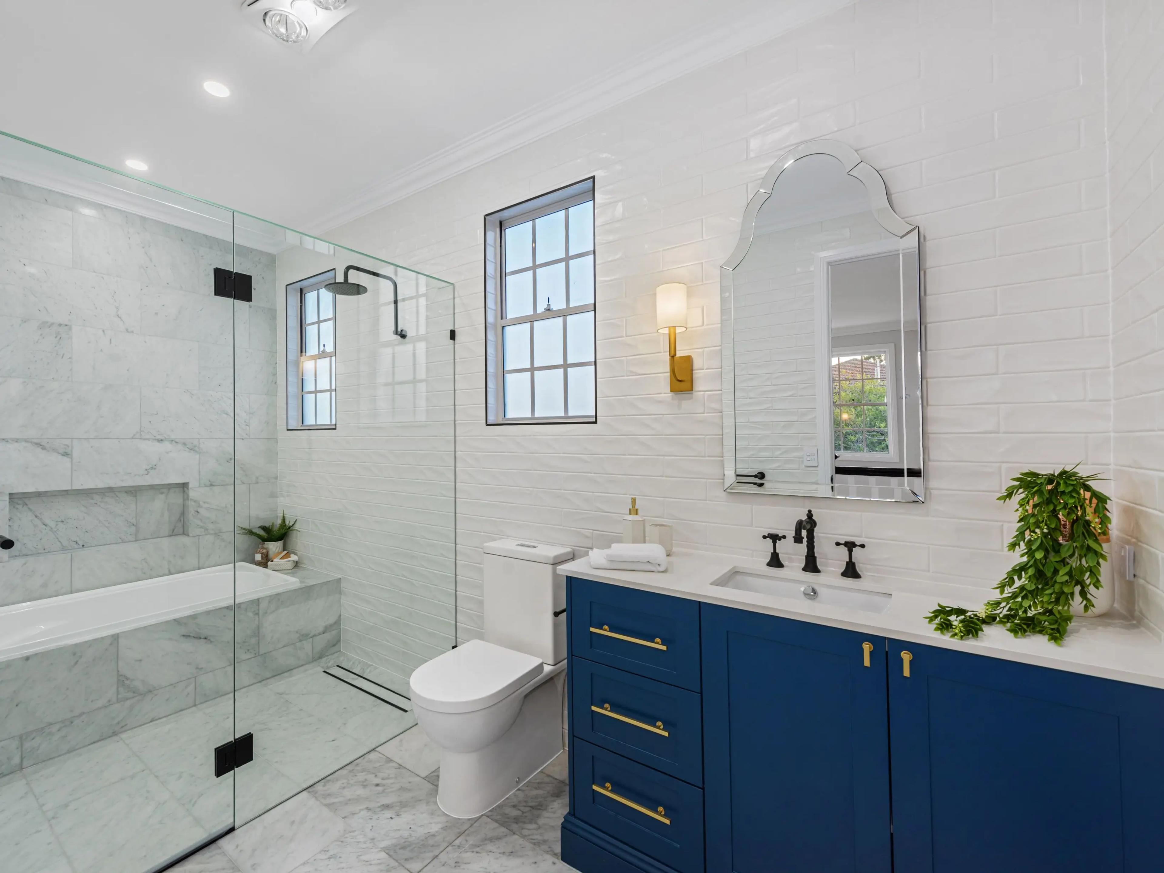 Bathroom with marble tiles, blue vanity and shower