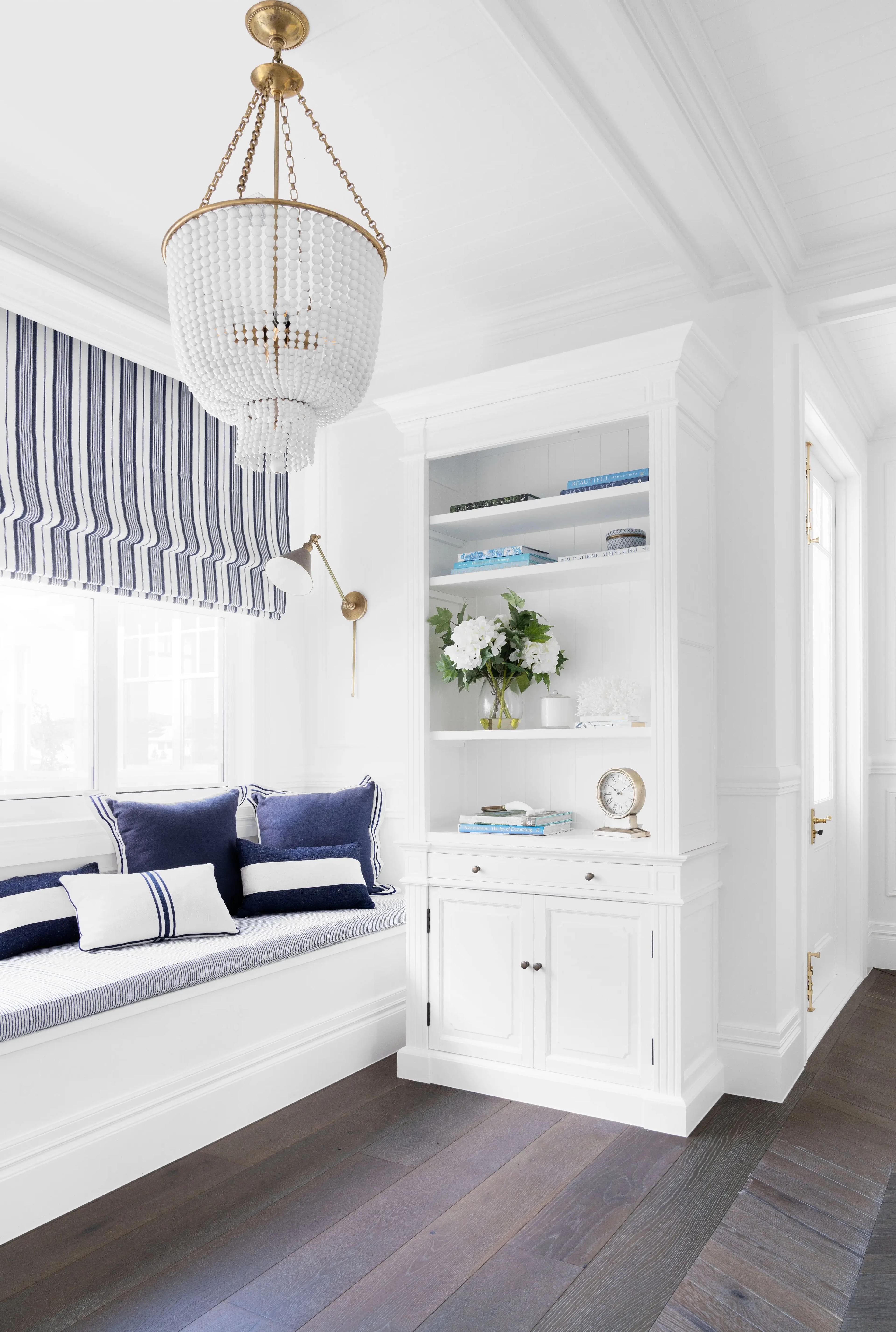 White window seat and built in shelving with beaded chandelier