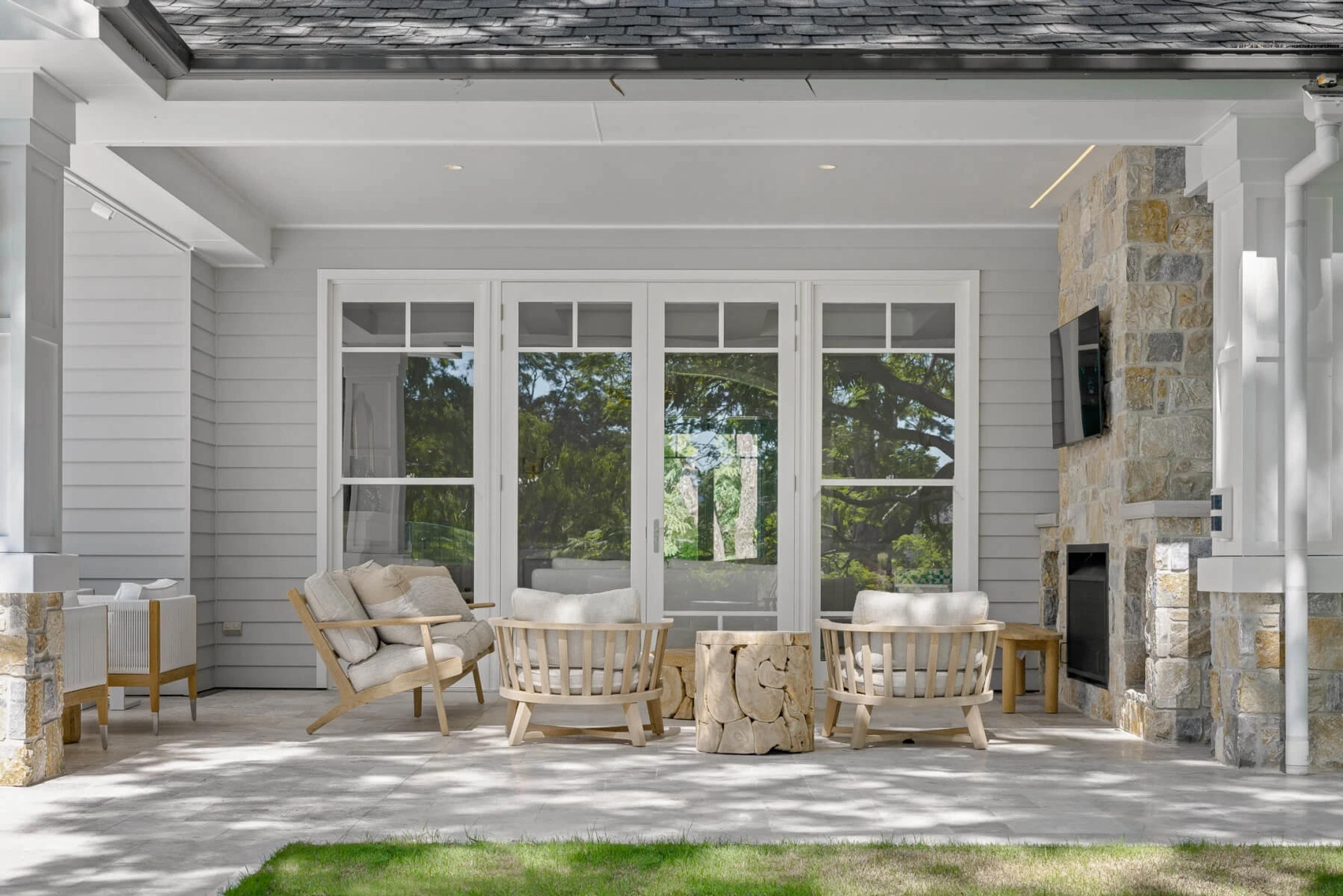 Outdoor lounge with timber chairs and stone fireplace