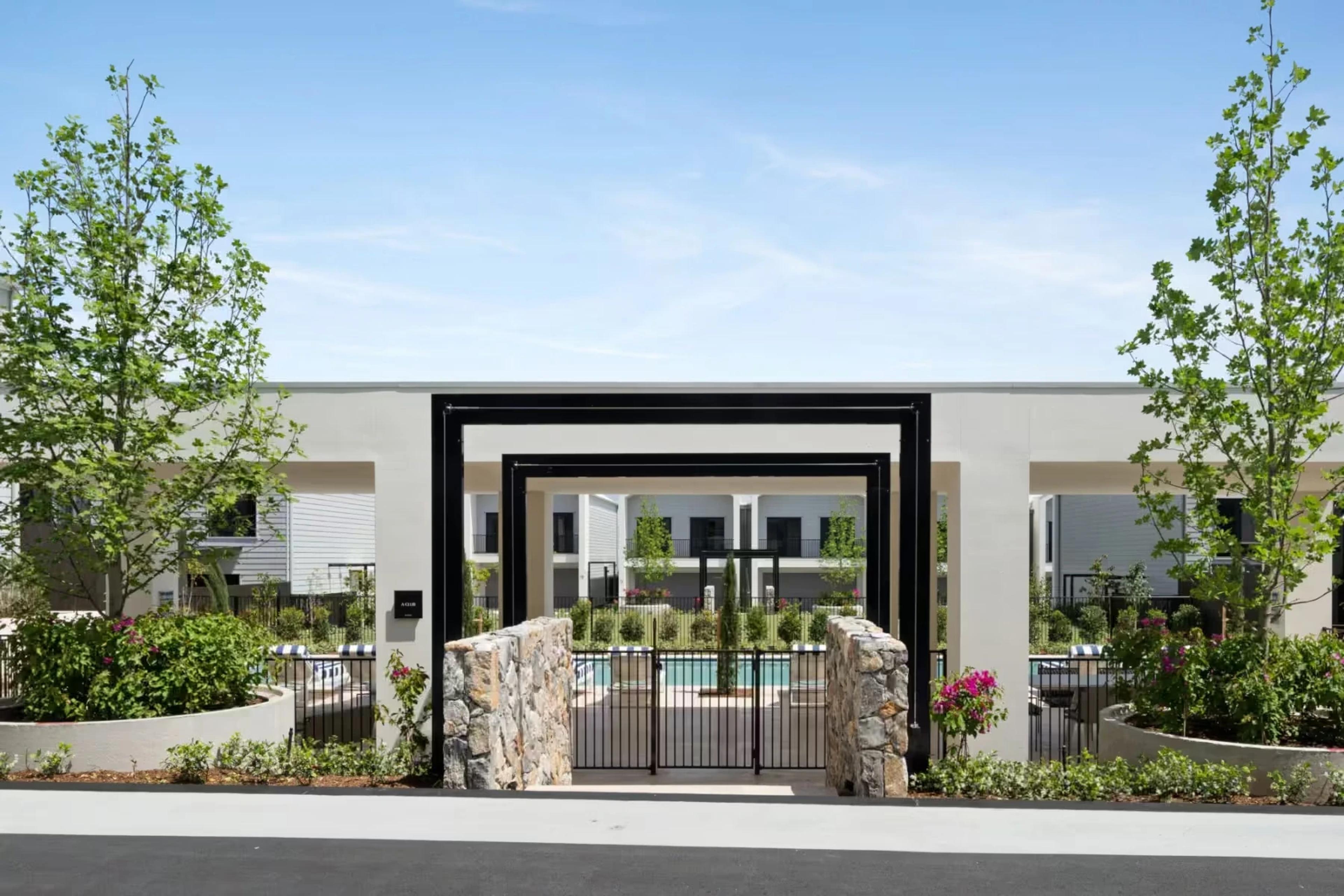 Black steel entry portal framing a landscaped pool courtyard