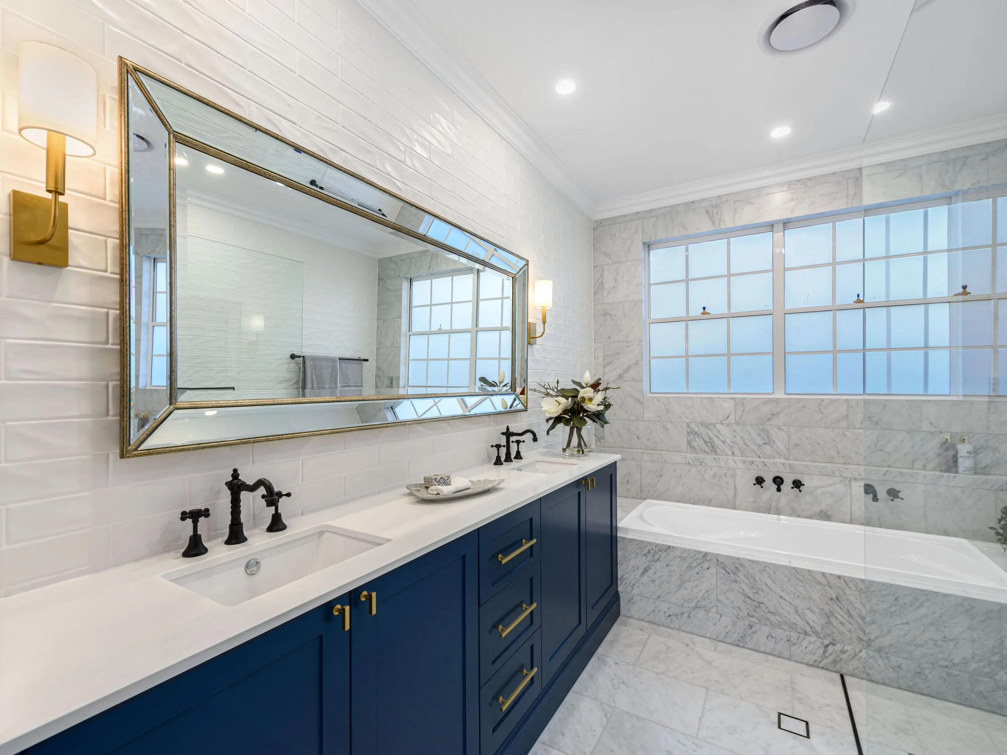 Bathroom with navy double vanity and marble bath