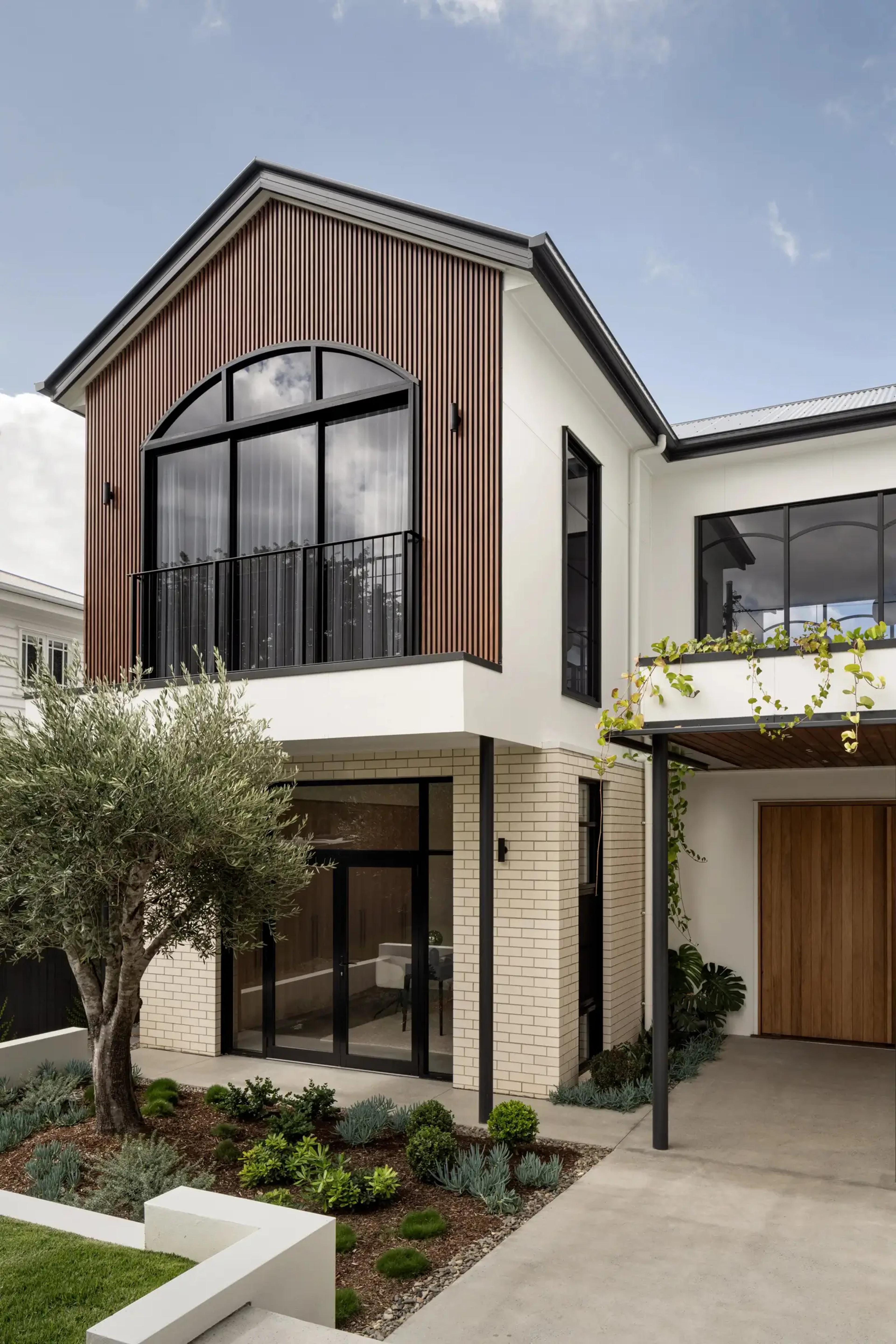 Entry facade with timber clad gable and arched upstairs window
