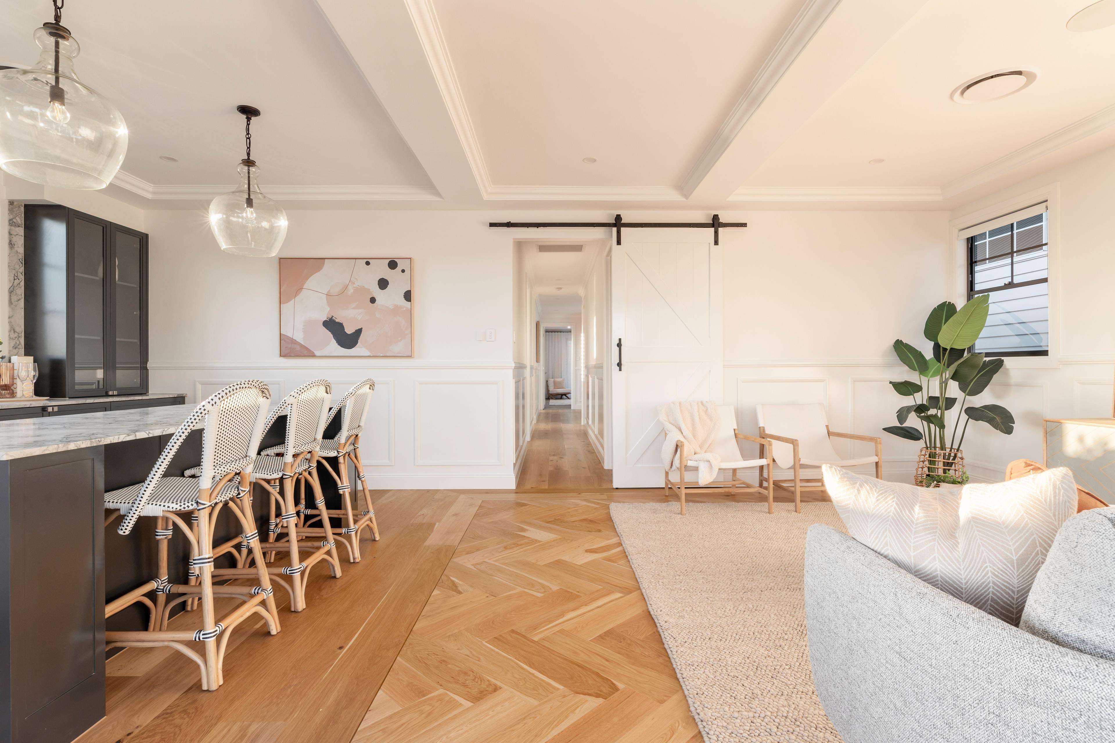 Open living and dining space with herringbone floors and barn door