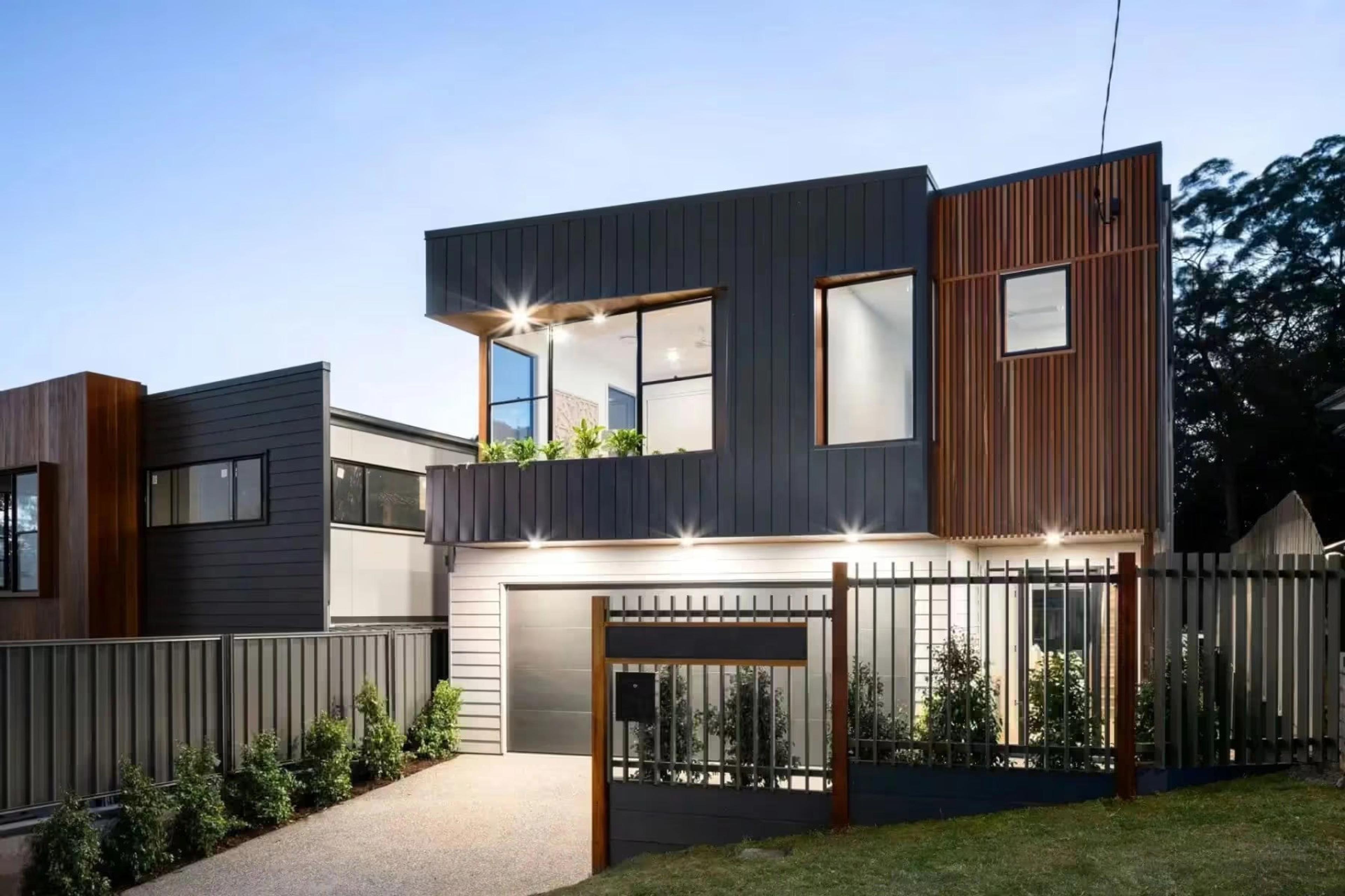 Front facade at dusk with dark cladding and fenced entry
