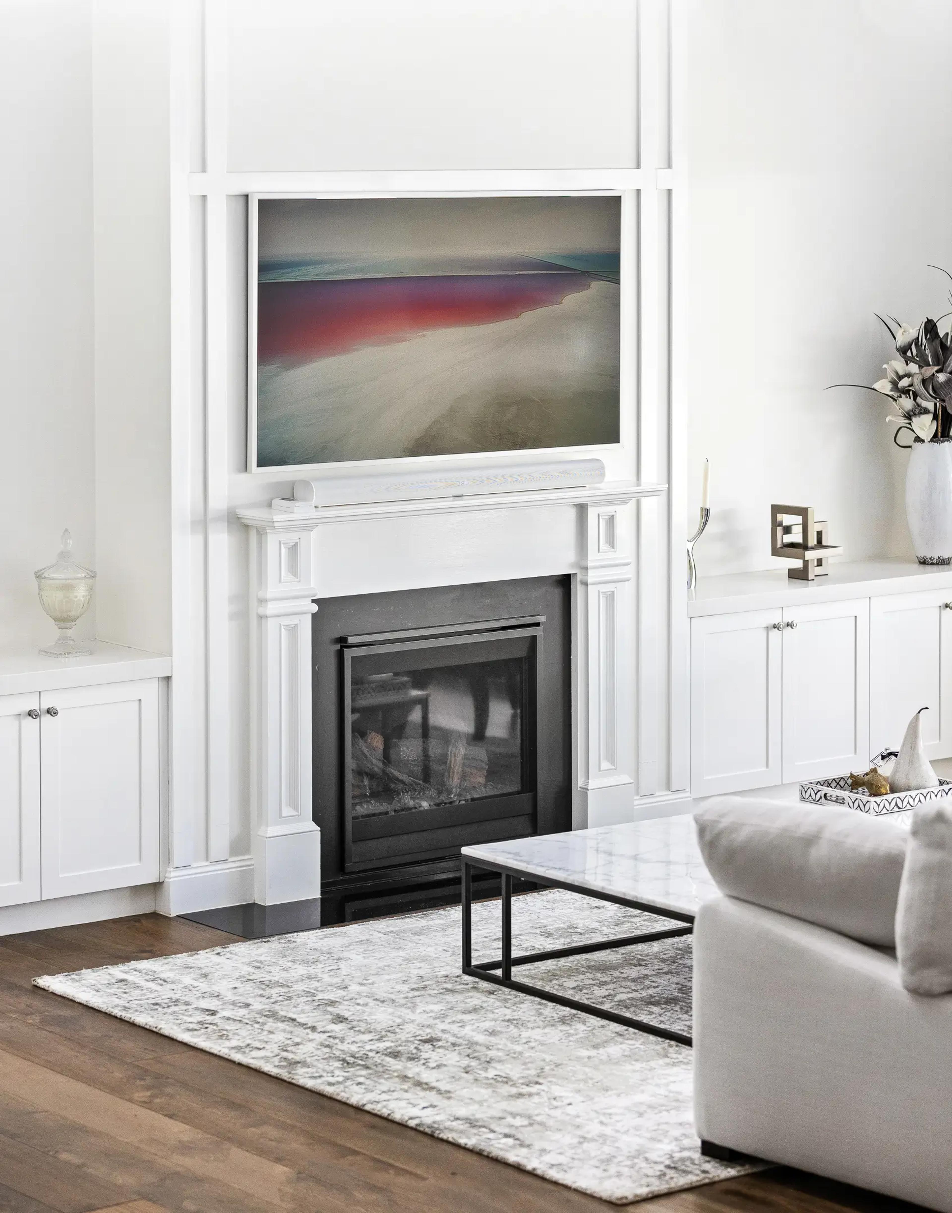 Living room fireplace with framed artwork and white joinery