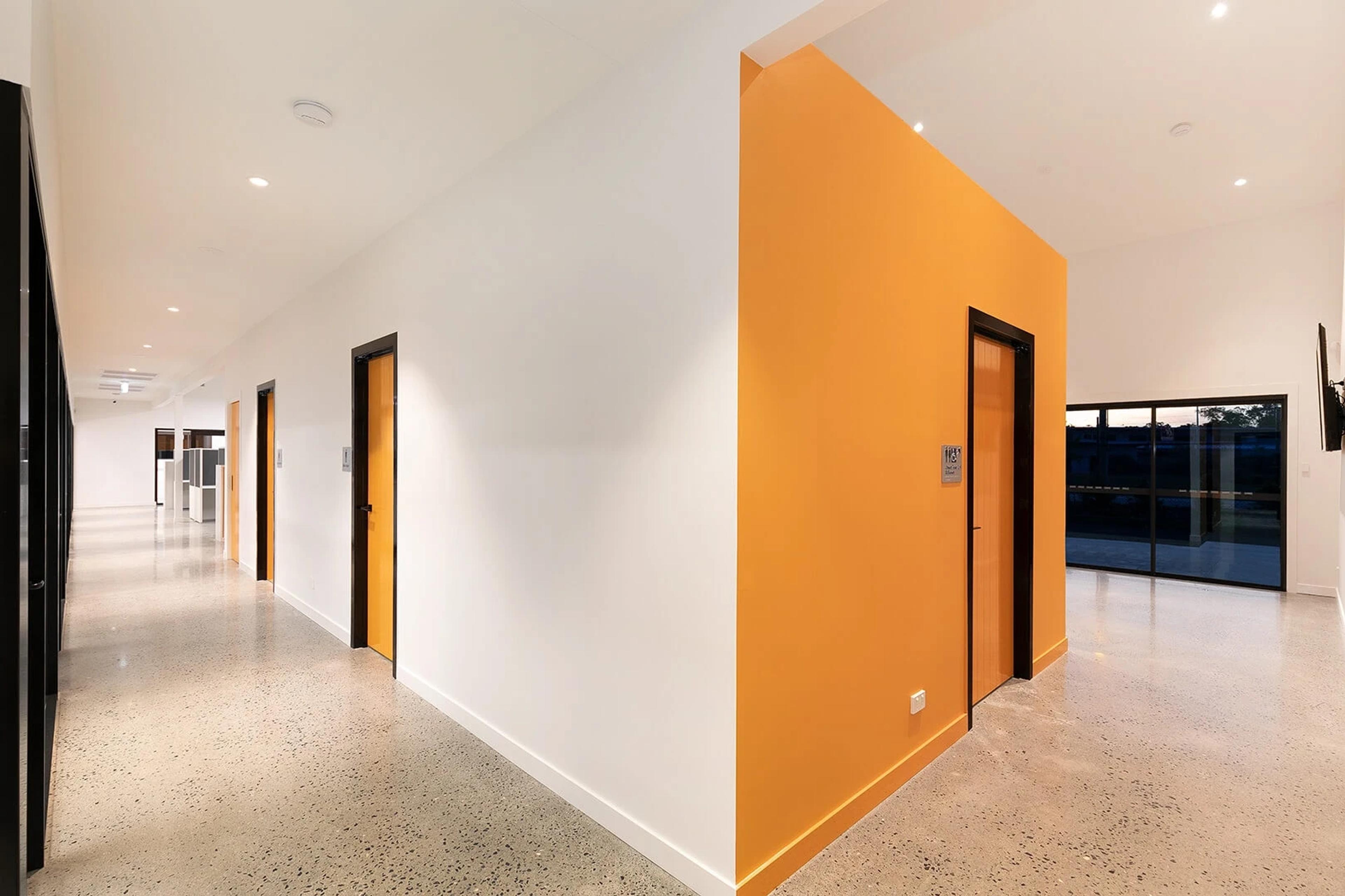 Corridor with orange feature wall and polished concrete floor