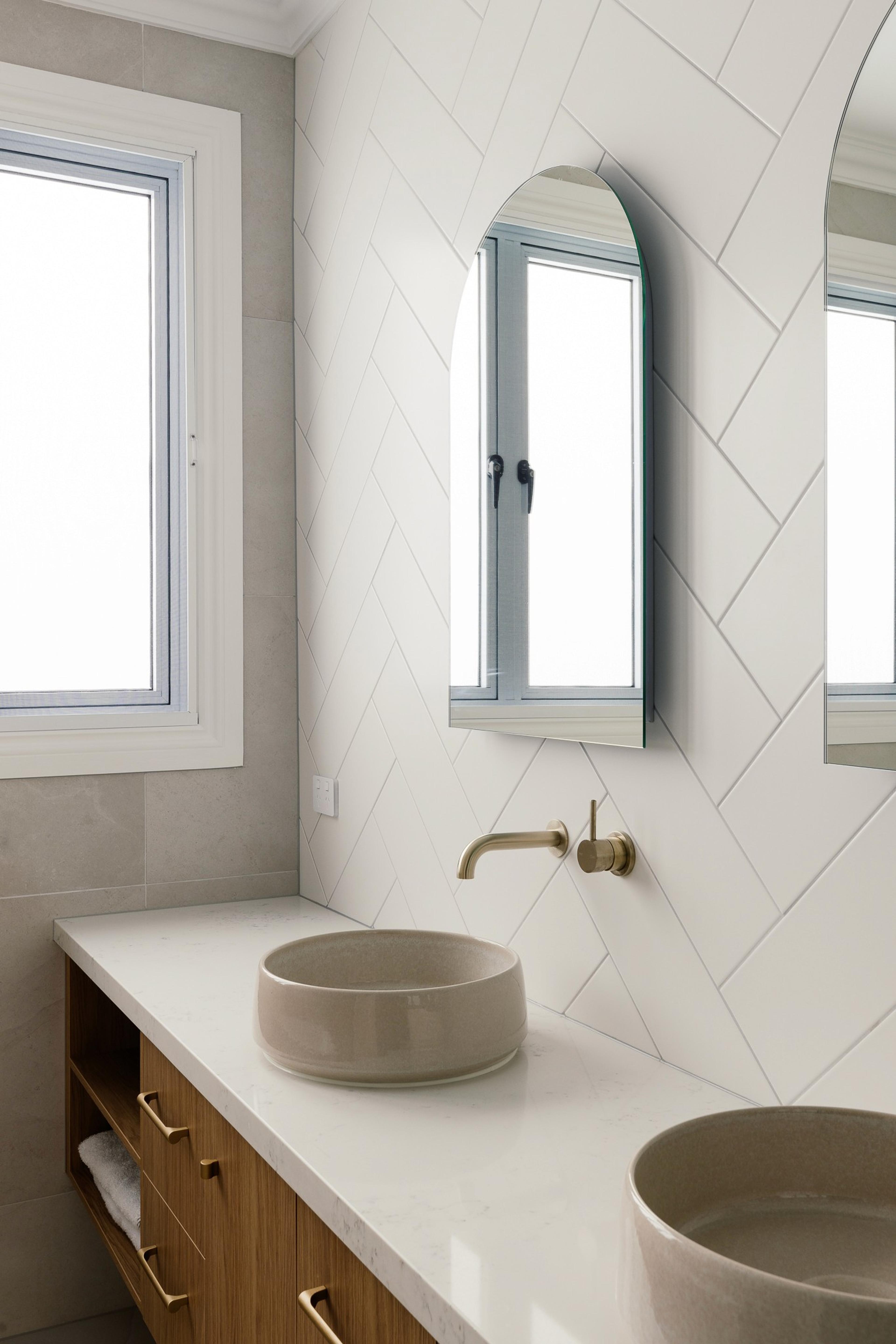 Bathroom vanity with stone basins, brass tapware and arched mirror