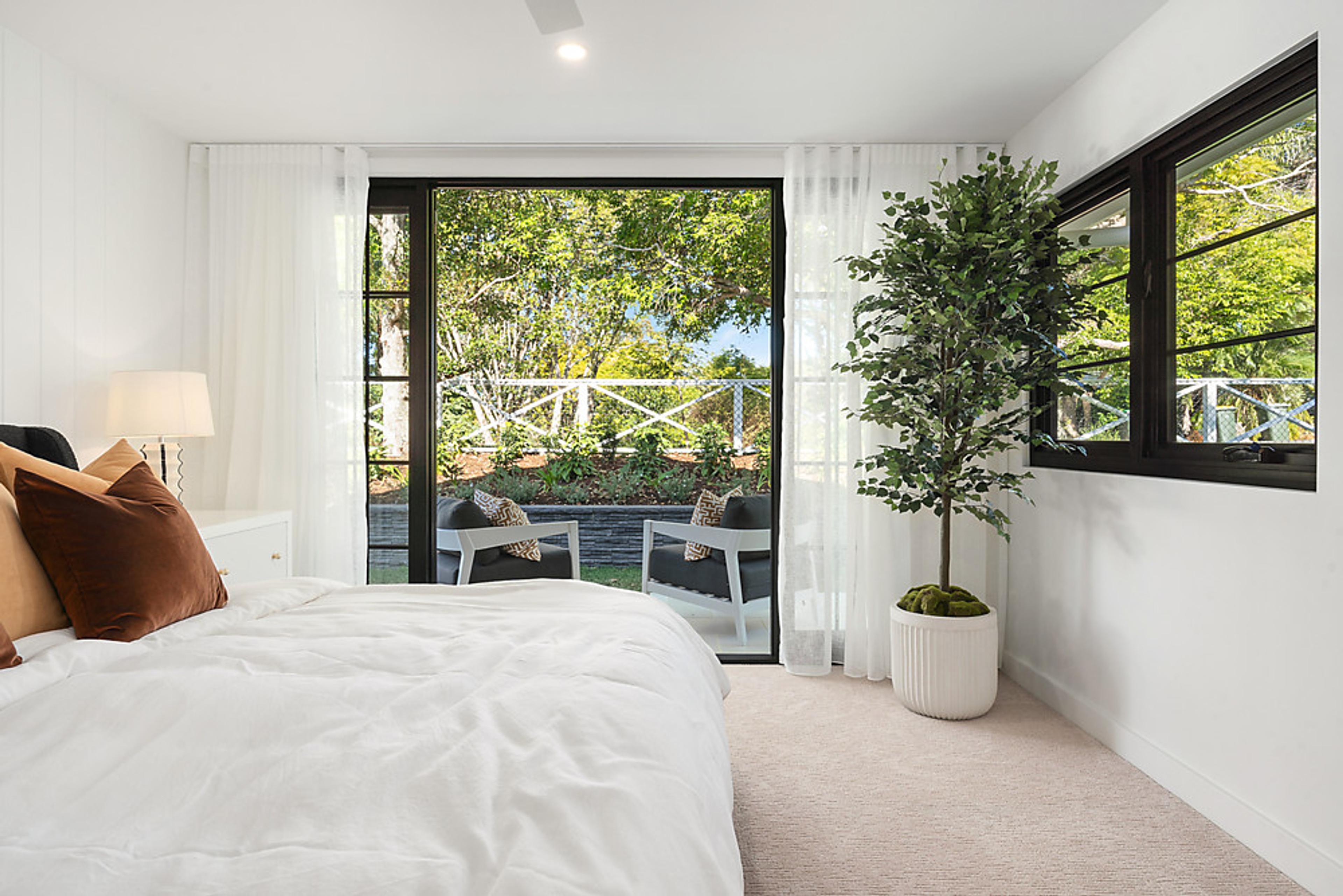 Bedroom opening through black-framed doors to a private patio and garden