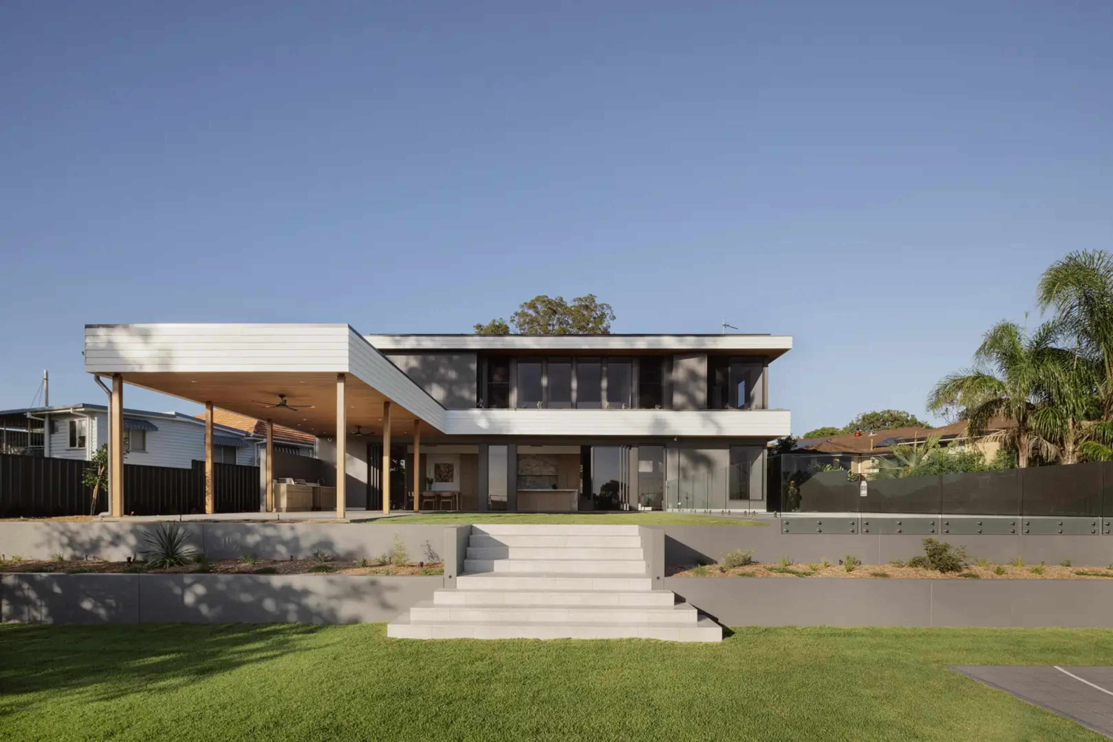 Rear of modern home with covered deck and lawn
