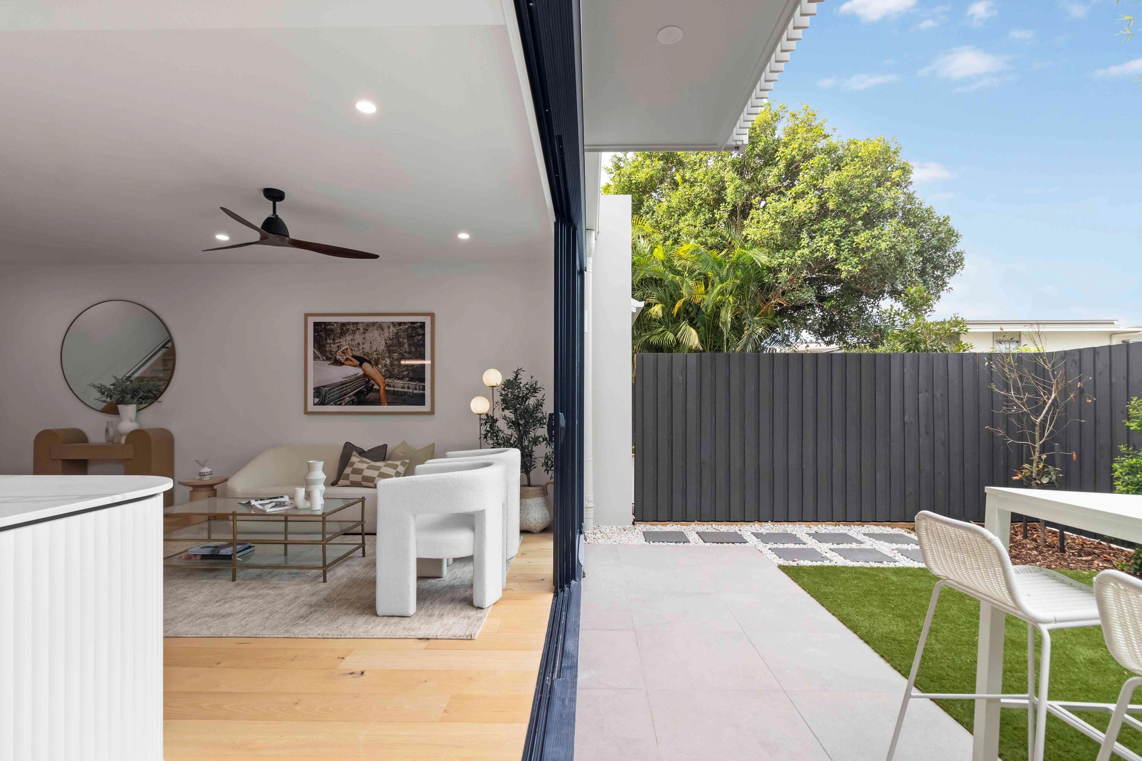 Living room opening to paved courtyard with dark timber fence