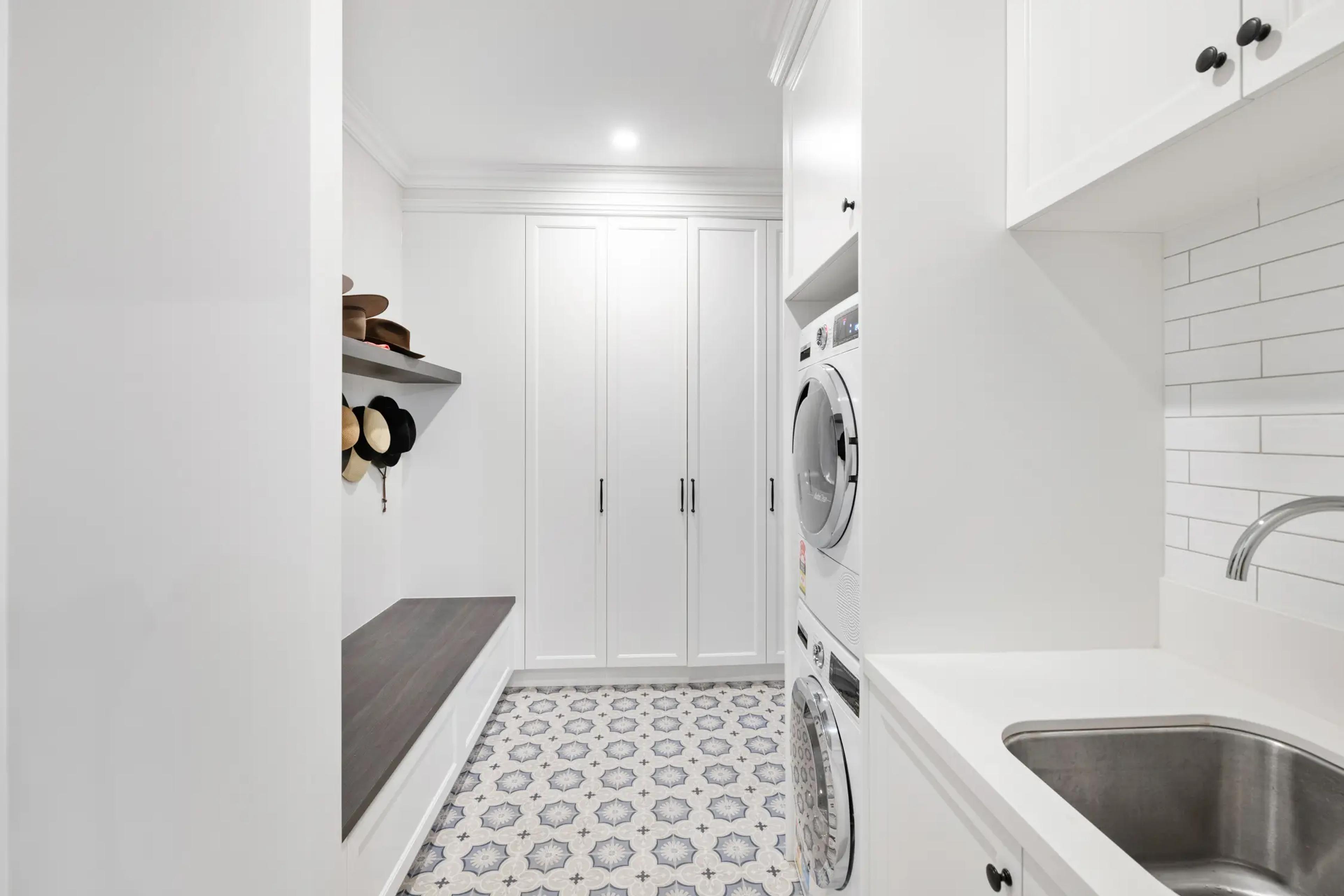 Laundry and mudroom with cabinetry and stacked machines