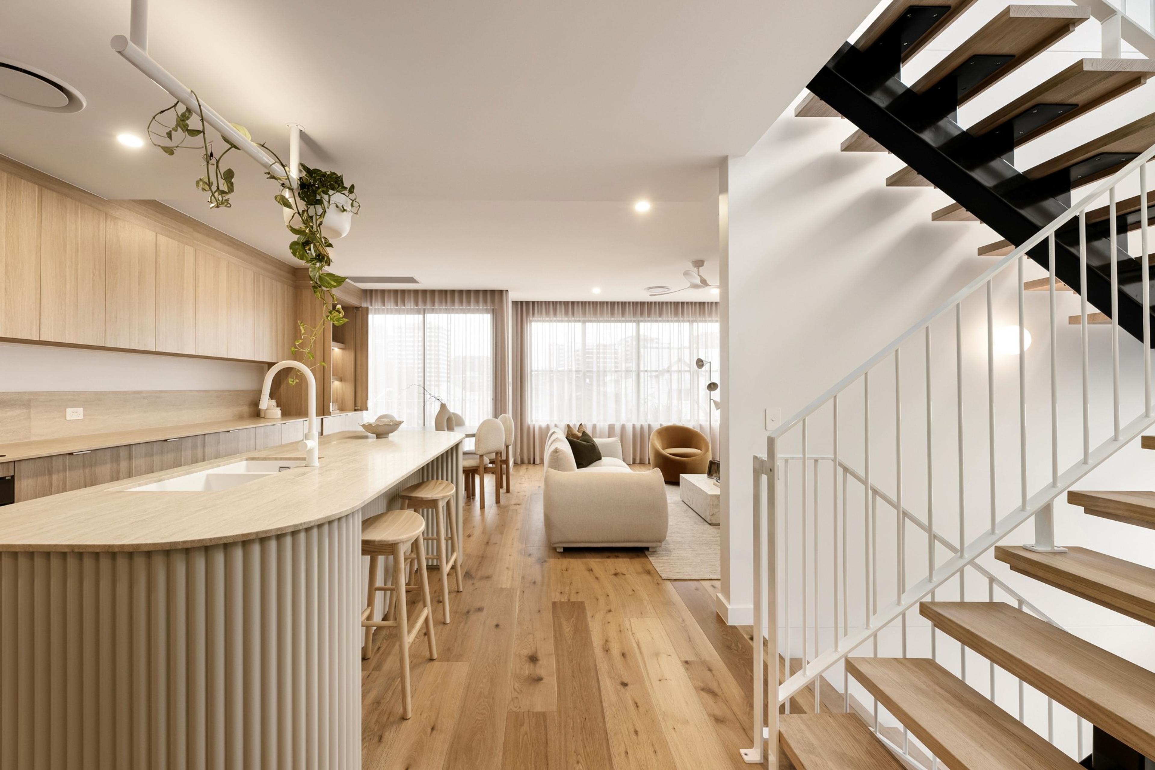 Open plan kitchen and living area beside a timber staircase