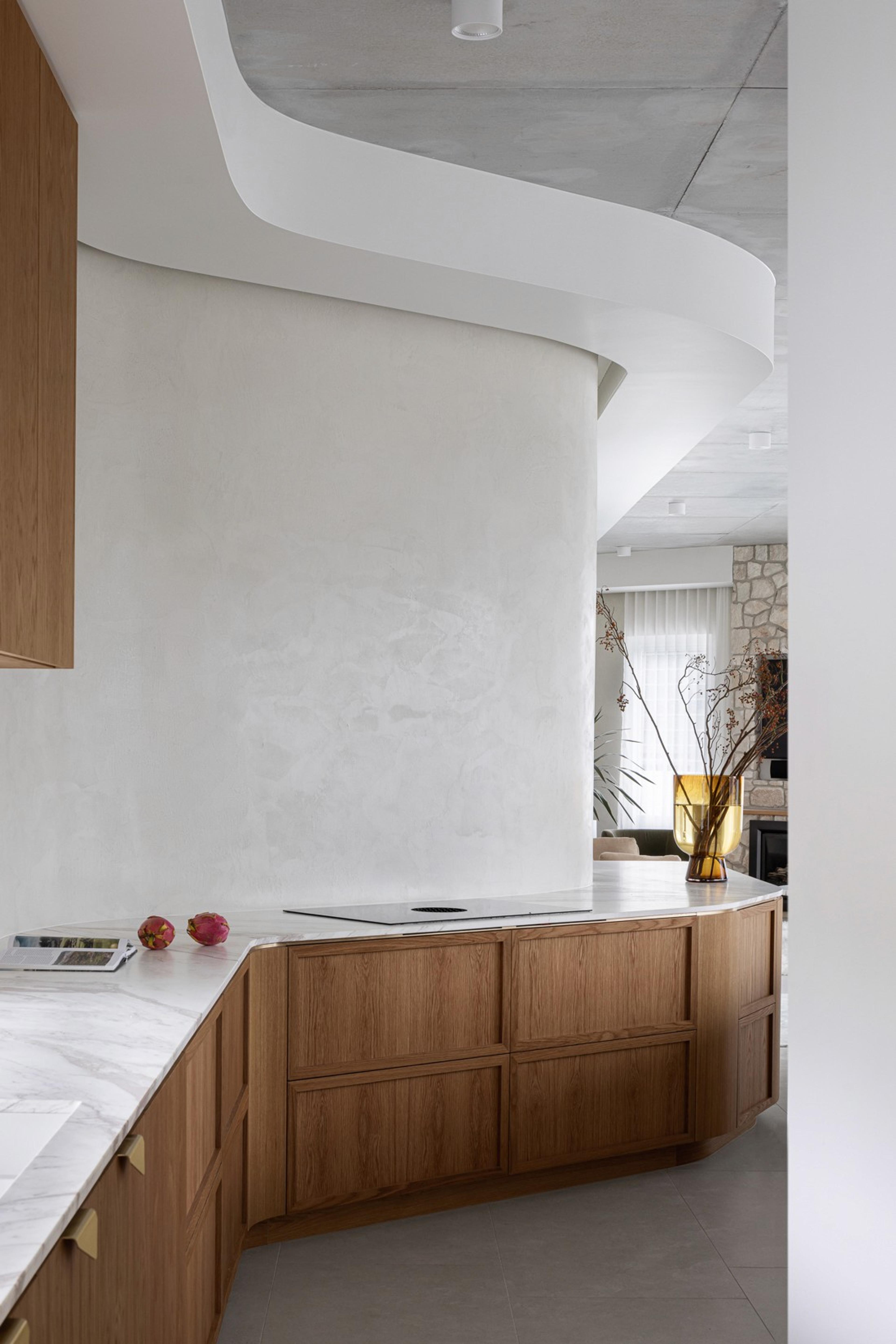 Curved kitchen joinery with timber cabinets and marble bench