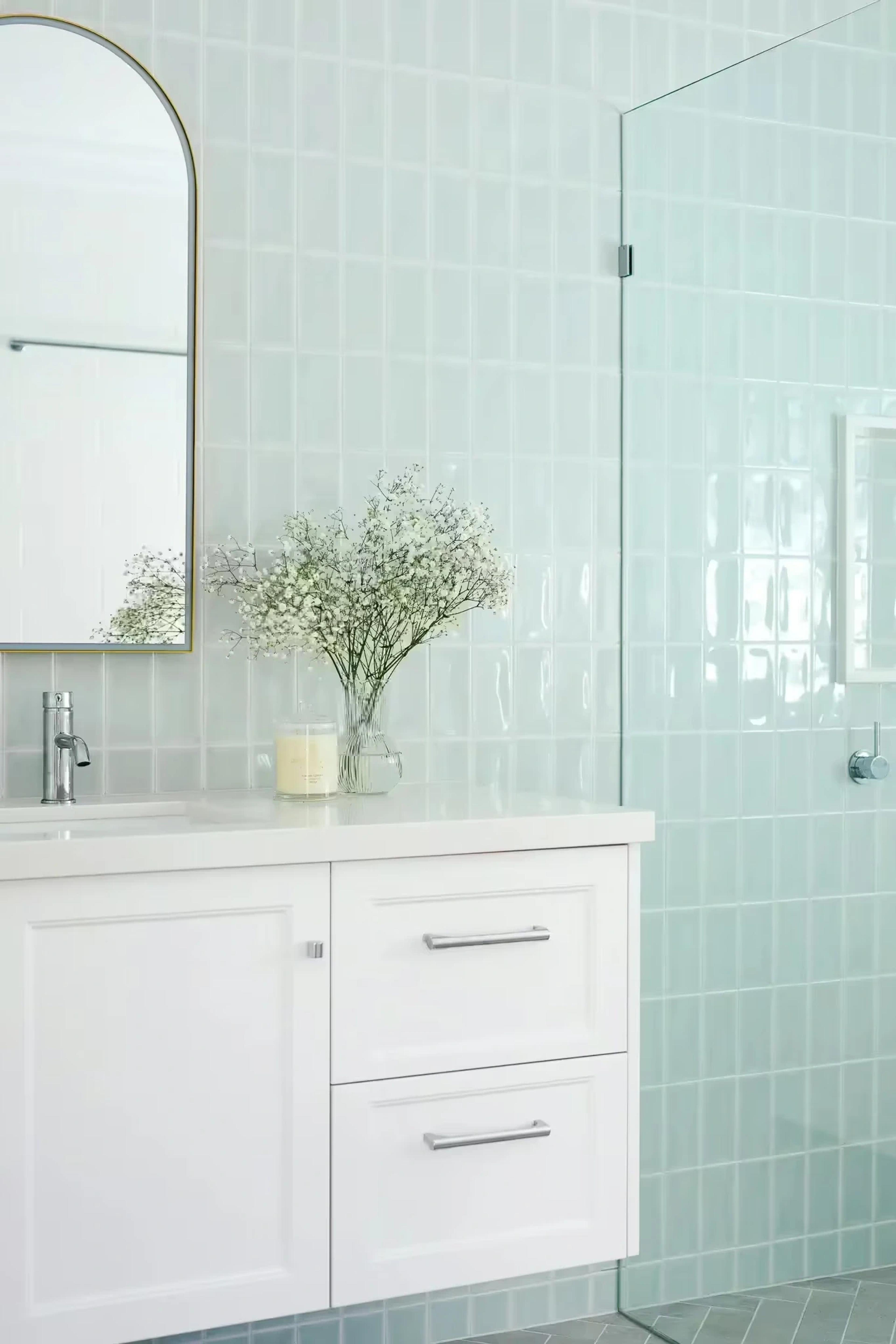 Bathroom with pale green tiles and white vanity