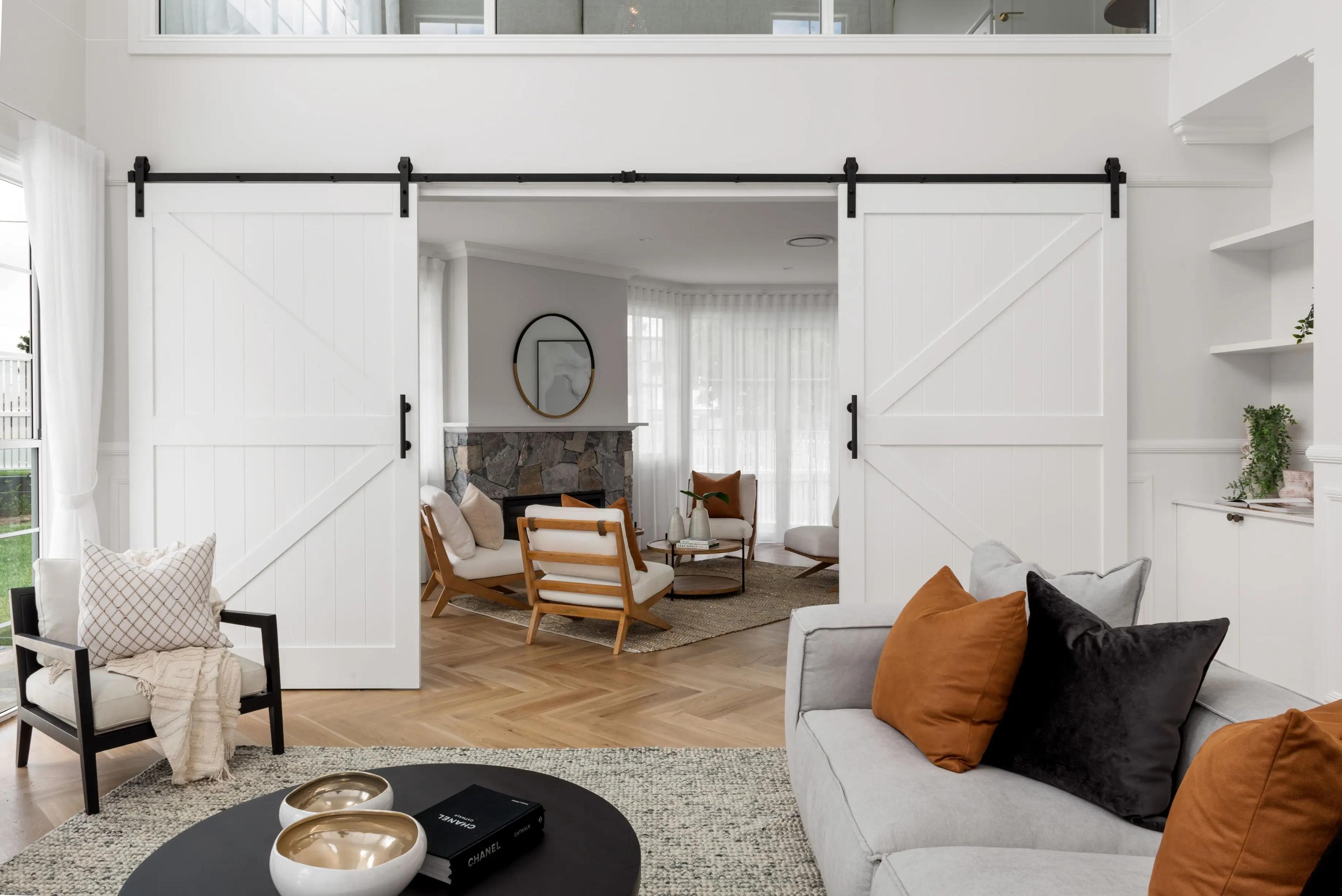 Living room with white barn doors opening to lounge and fireplace