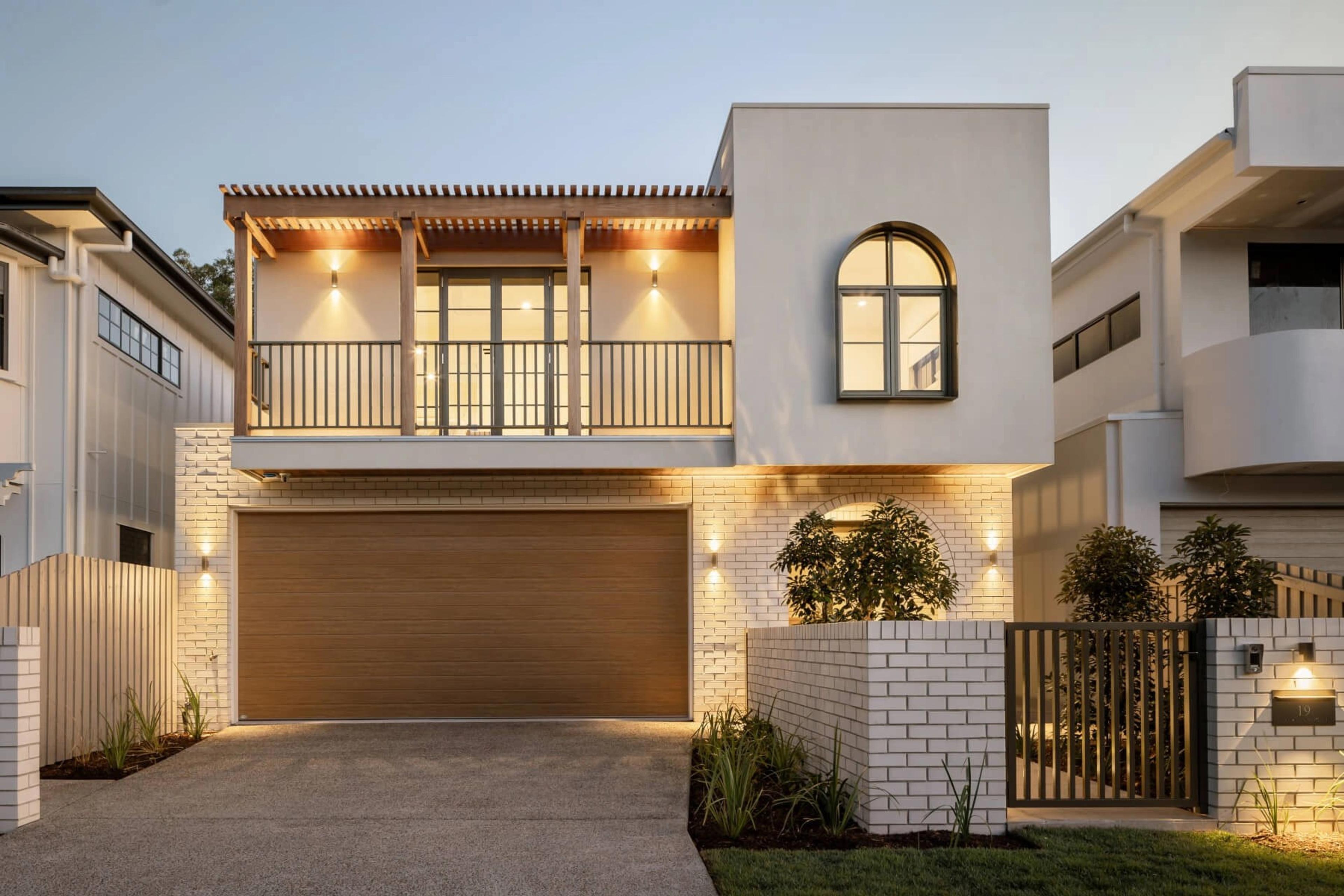 Dusk front elevation with lit balcony pergola and timber garage