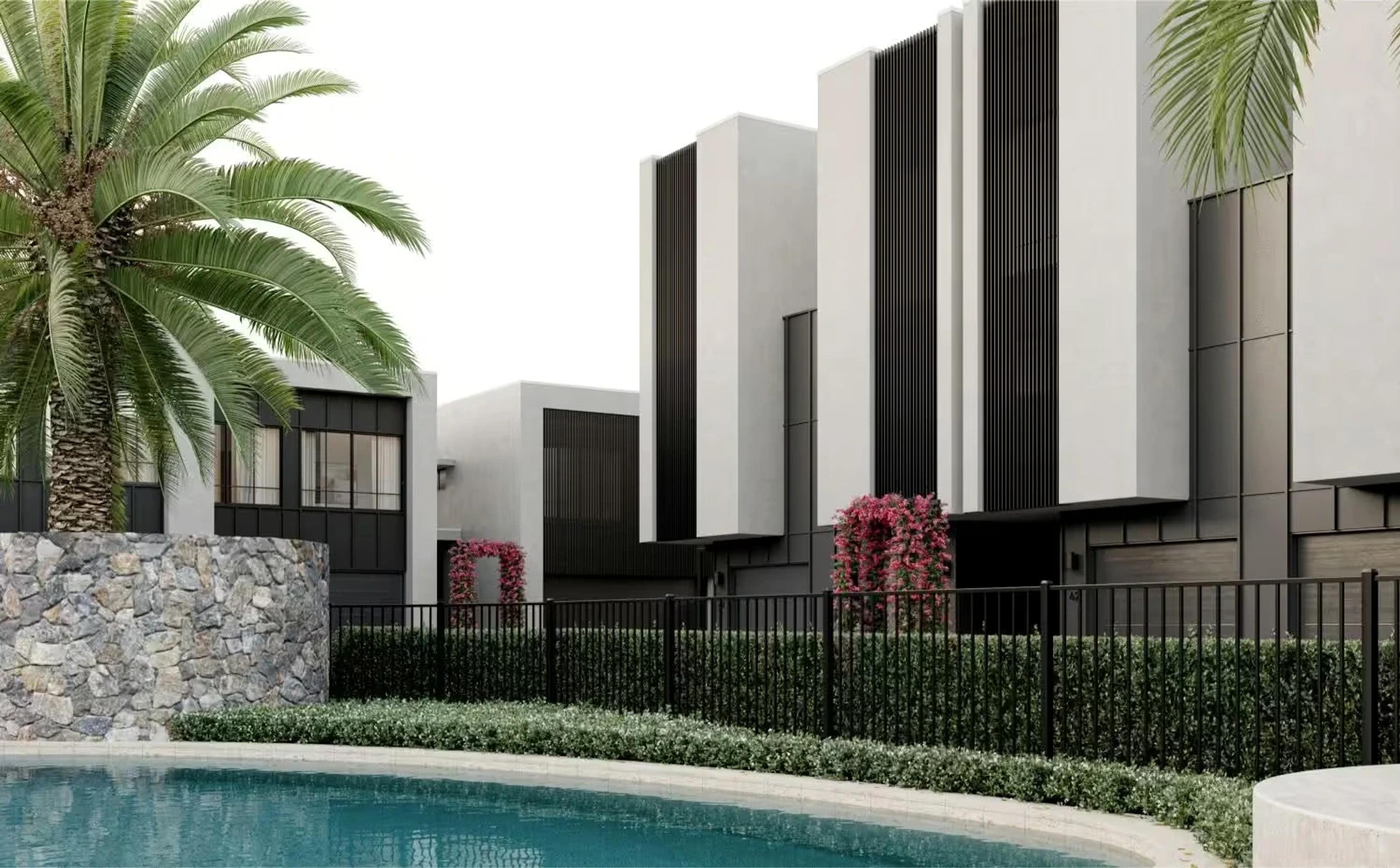 Poolside view of townhouses with stone wall and pool fence