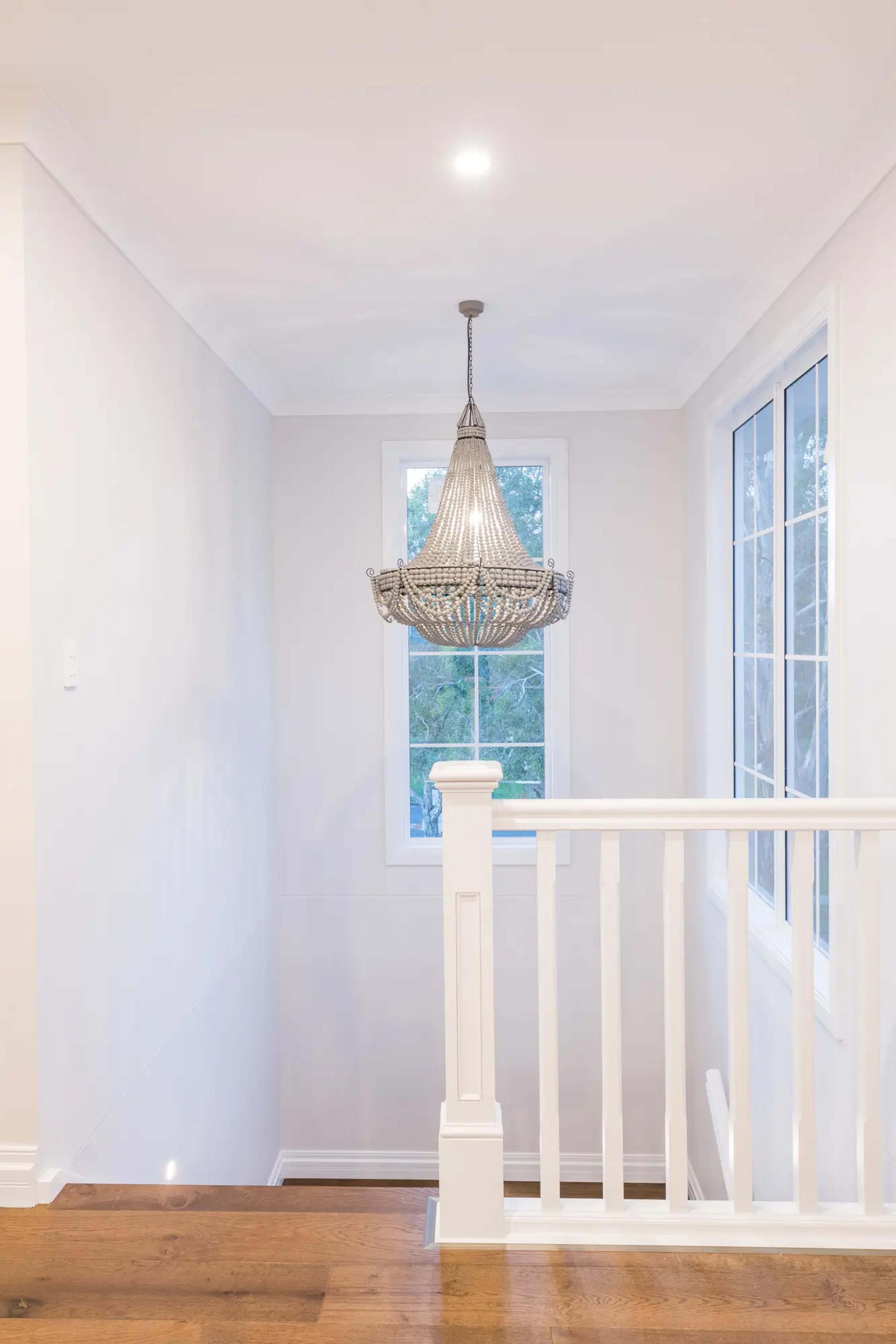 Stairwell landing with beaded chandelier and white balustrade