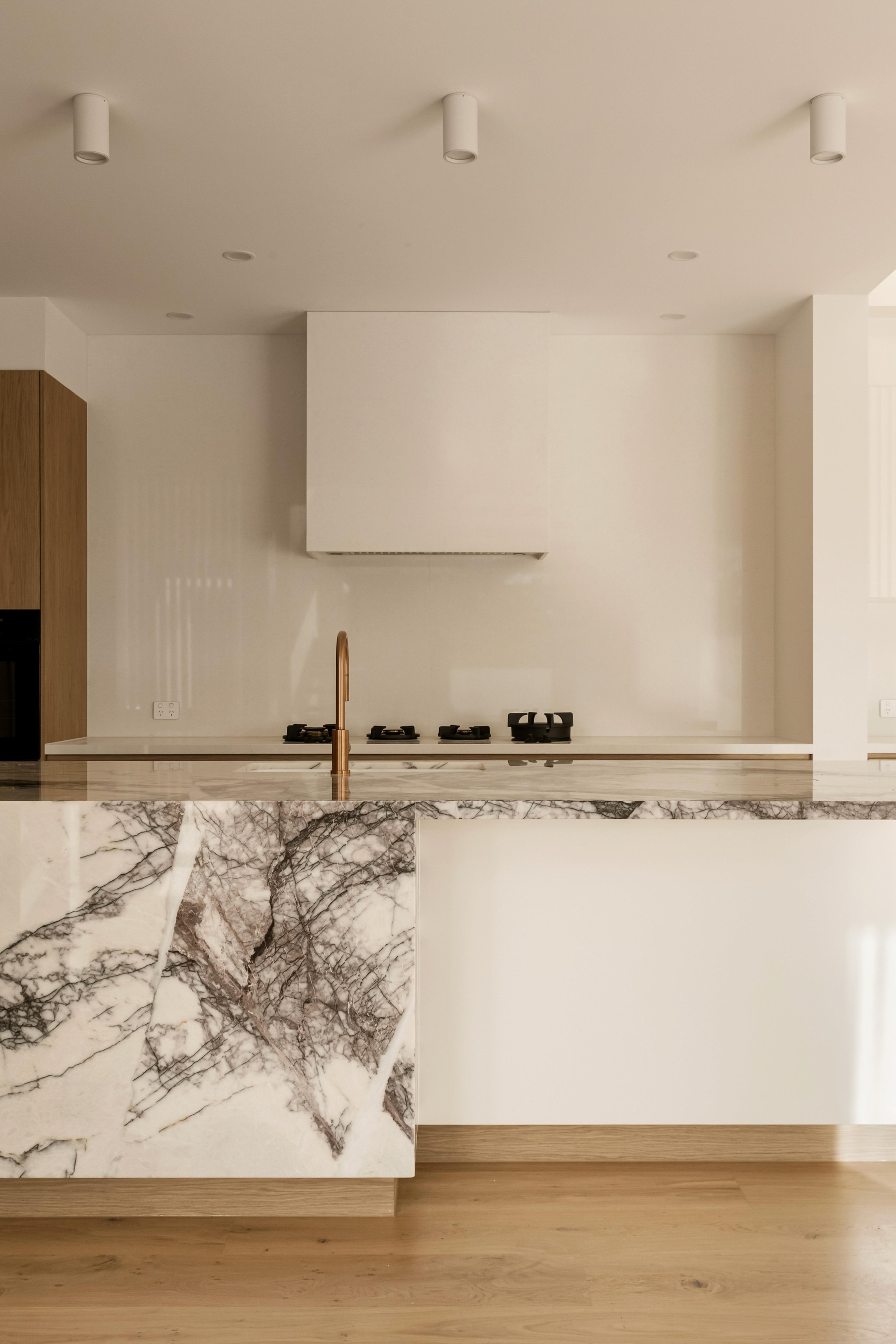 Kitchen marble island with brass tap and gas cooktop