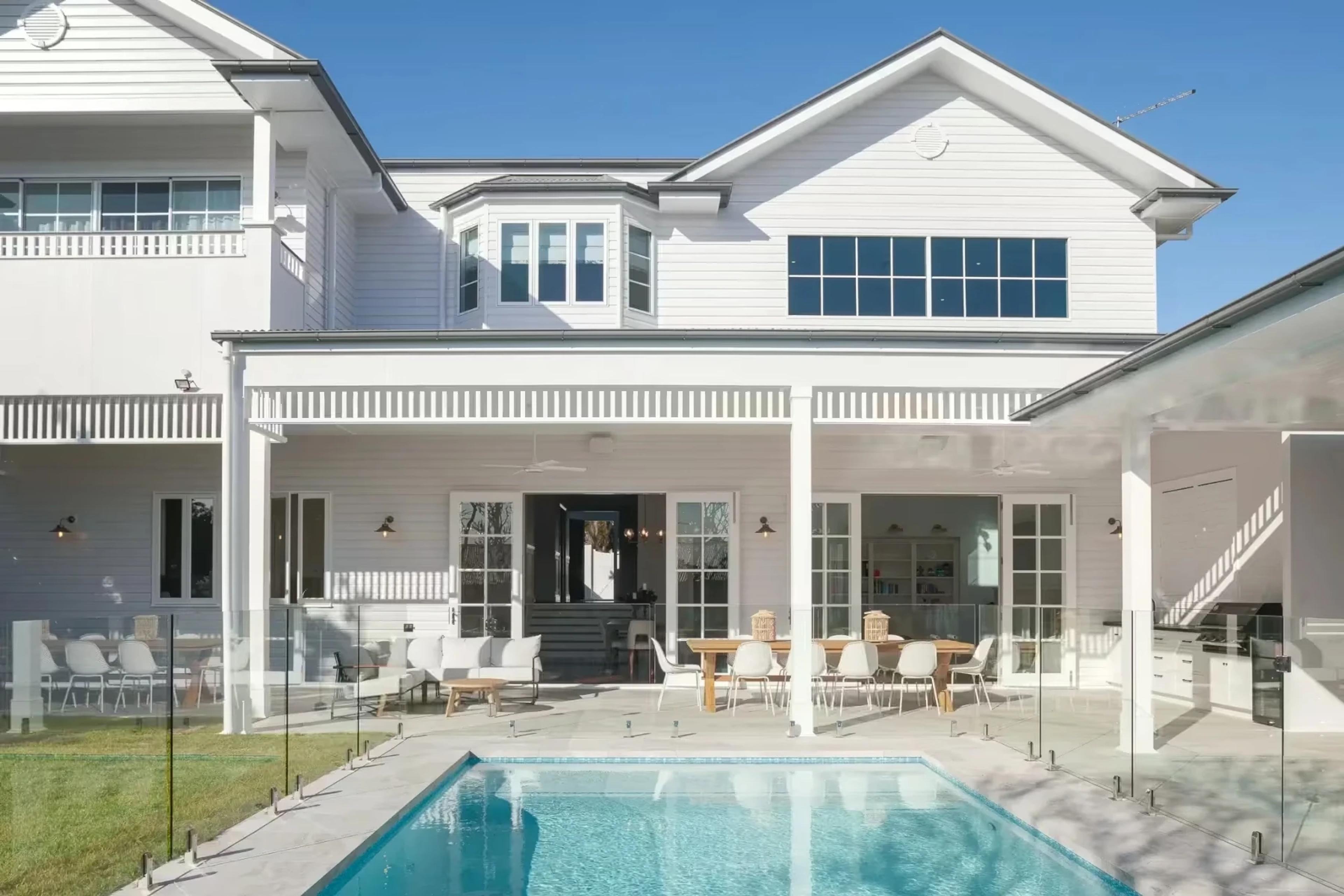 Rear facade of white weatherboard home with pool and verandah
