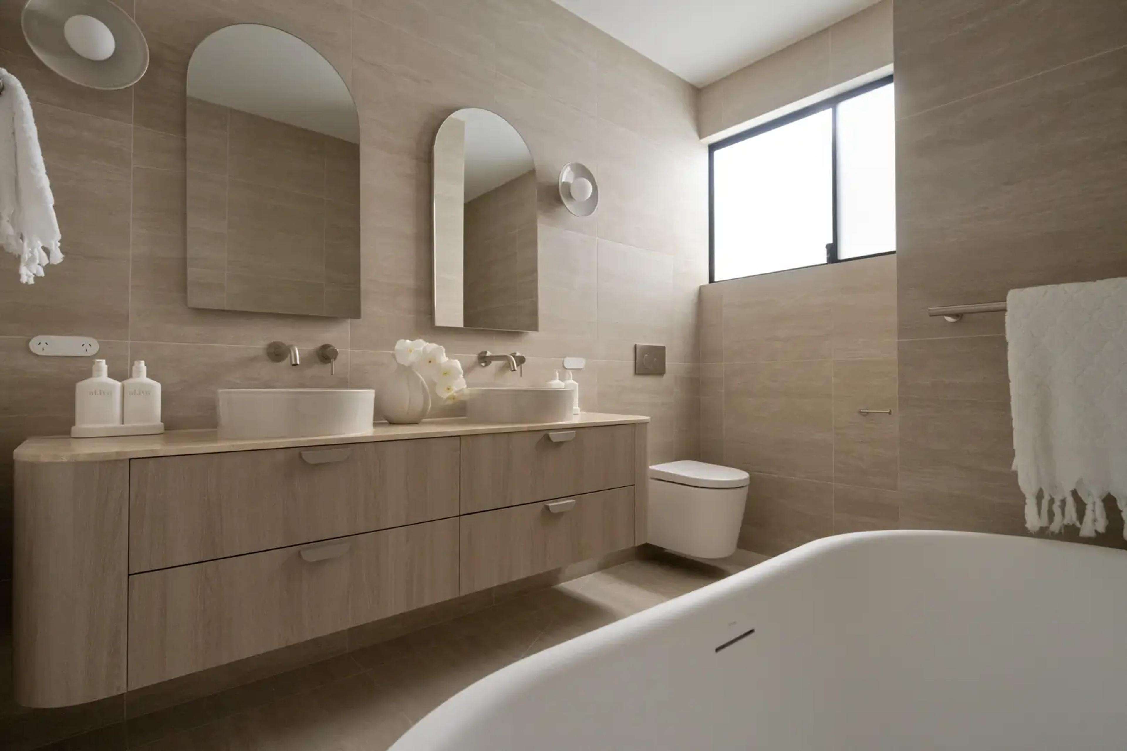 Bathroom with twin basins, arched mirrors and bath