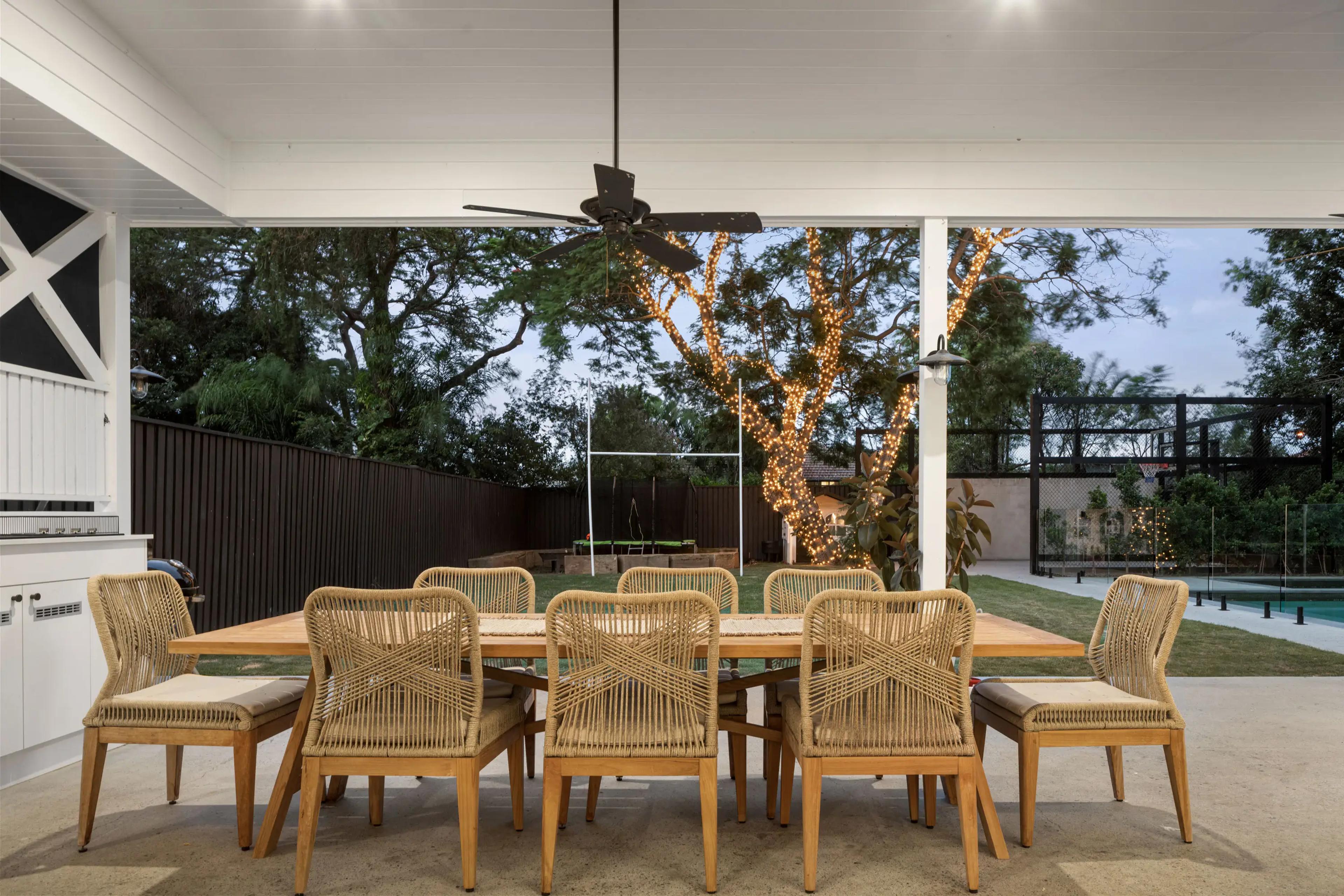 Covered outdoor dining area overlooking backyard with festoon lit tree